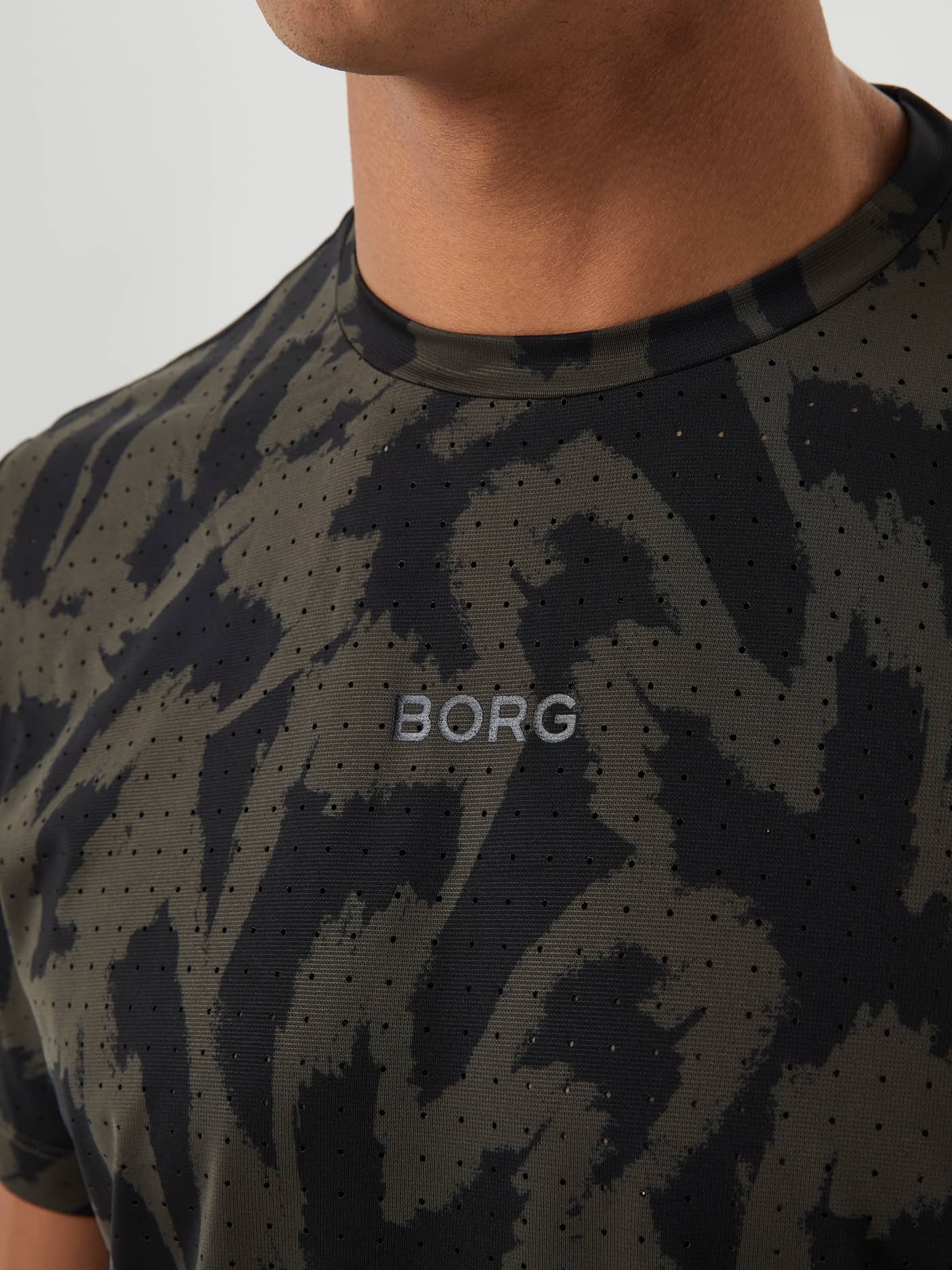 Close-up of the Borg Running Perforated T-Shirt for men in green and black Running Aop (Multi) featuring a grey logo. - Image 5