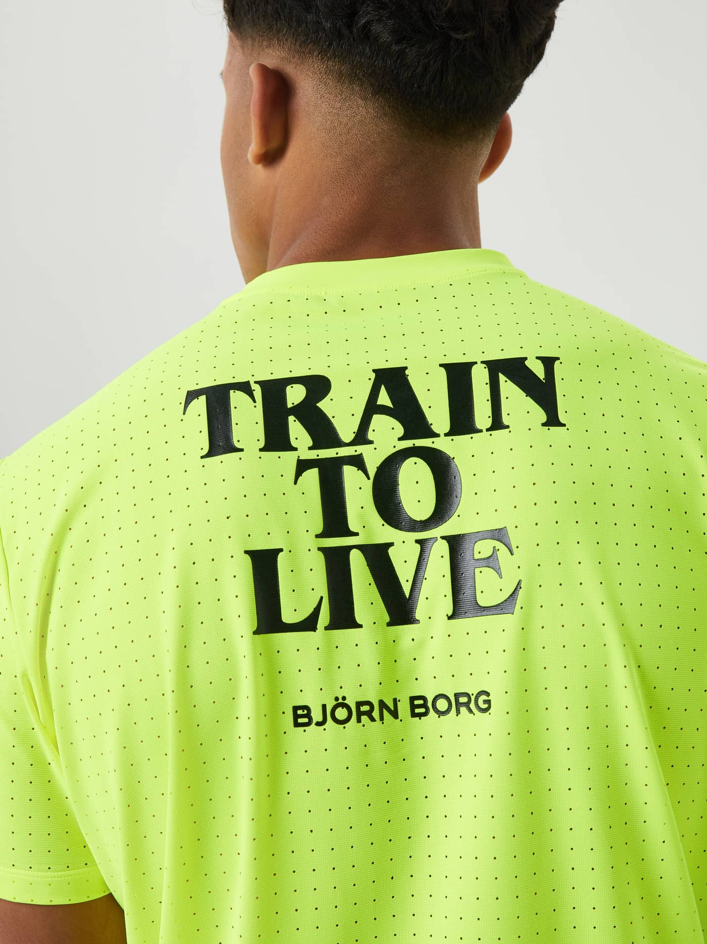 Närbild bakifrån på Borg Running Perforated T-Shirt i Safety Yellow (Gul) med svart 'TRAIN TO LIVE'-tryck för löpning. - Image 4