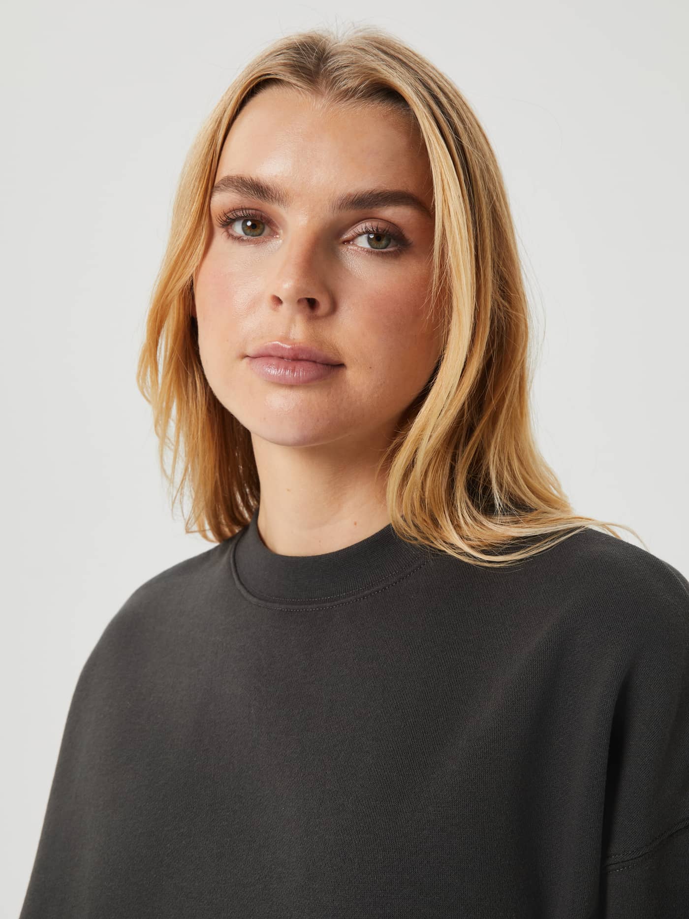 Close-up of a model wearing the Björn Borg Studio Oversized Crew in Peat (Green) with a ribbed round neck. - Image 6