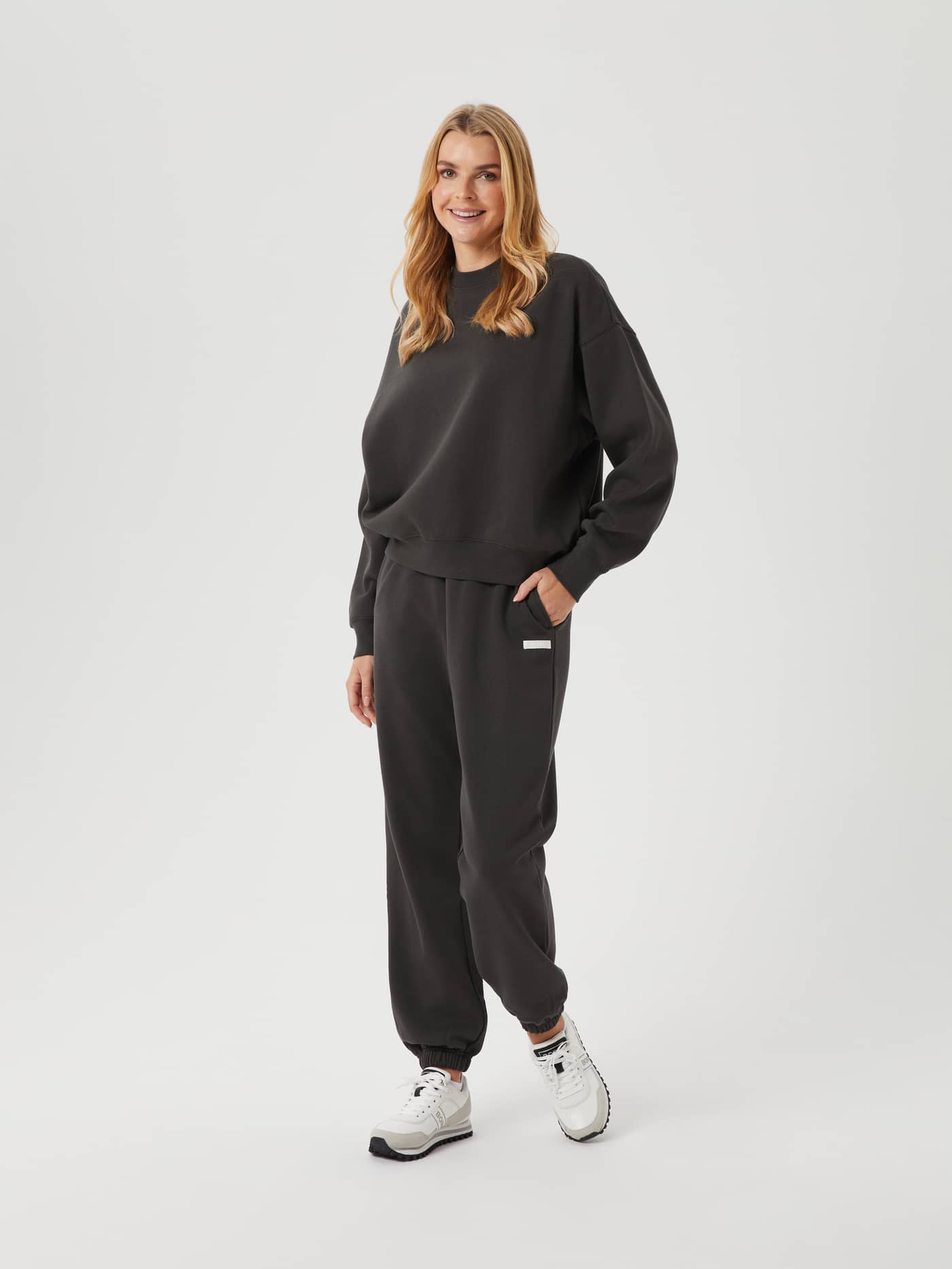 Full-body front view of a woman wearing the cotton Björn Borg Studio Oversized Crew in Peat (Green) with matching pants. - Image 3