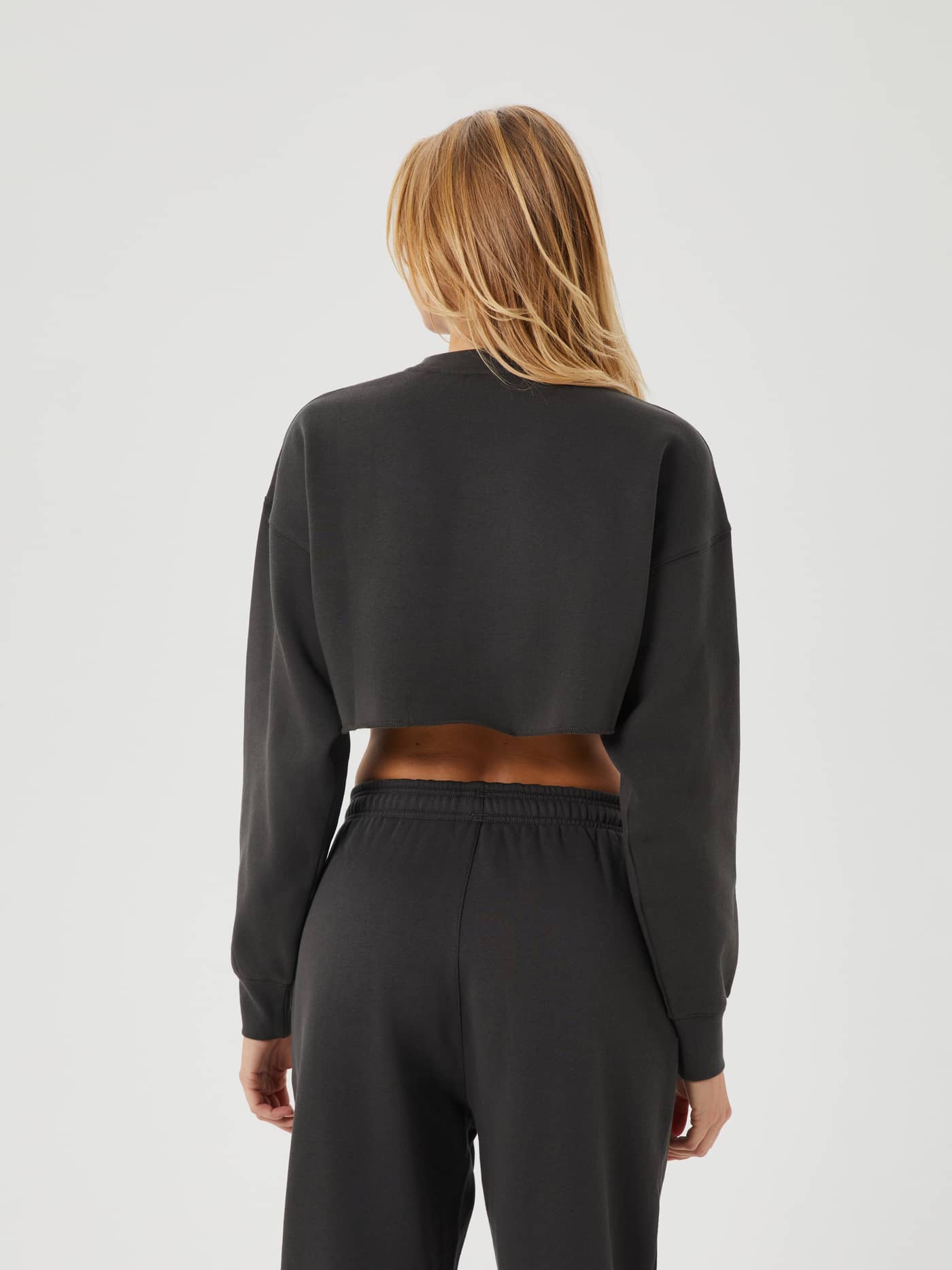 Back view of a woman wearing the Peat (Green) Studio Oversized Cropped Crew, featuring a relaxed and stylish cropped fit. - Image 2