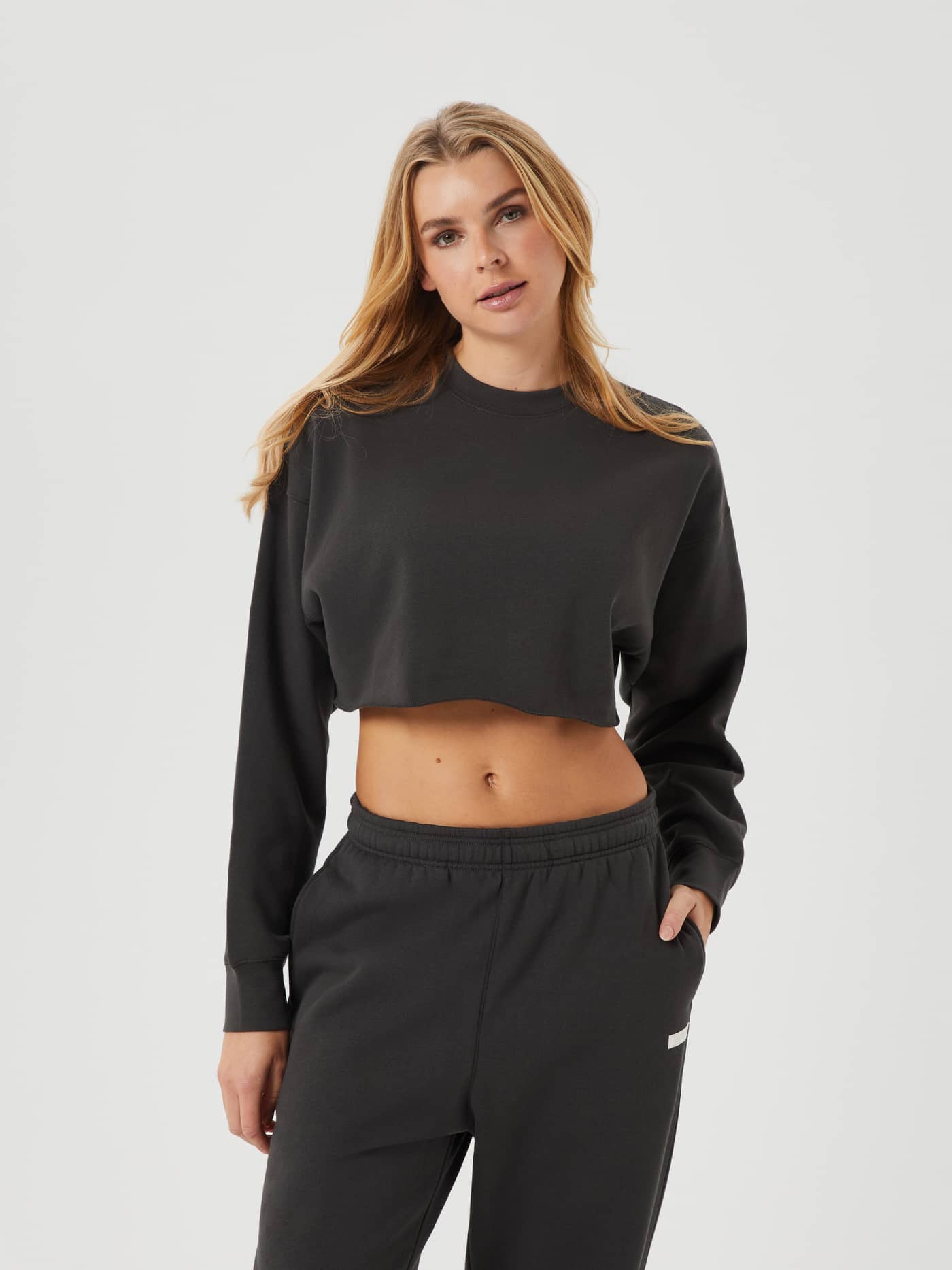 Front view of a woman wearing the Studio Oversized Cropped Crew in Peat (Green) with a cropped fit and raw edges. - Image 1