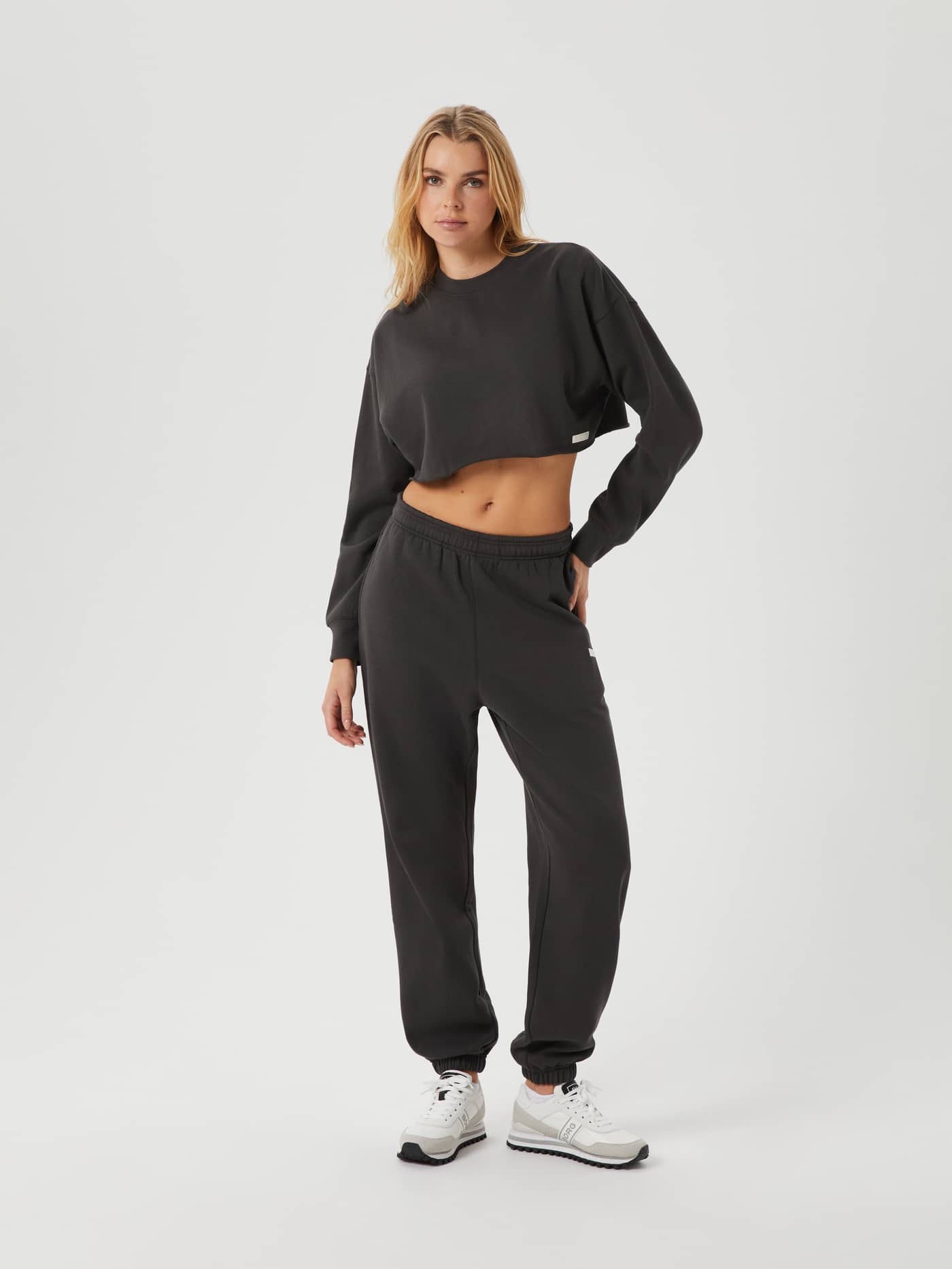 Full-body front view of a woman wearing the Björn Borg Studio Oversized Cropped Crew in Peat (Green) with a white logo label. - Image 3