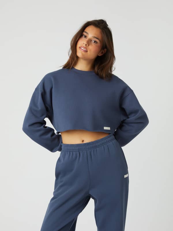 Front view of a model in the Björn Borg Studio Oversized Cropped Crew in Nightshadow Blue (Blue) with a white logo label.