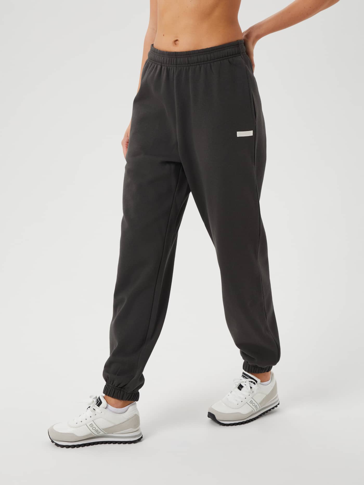 Front view of a model wearing the Studio Oversized Pants in Peat (Green) with oversized fit and white logo for training. - Image 2