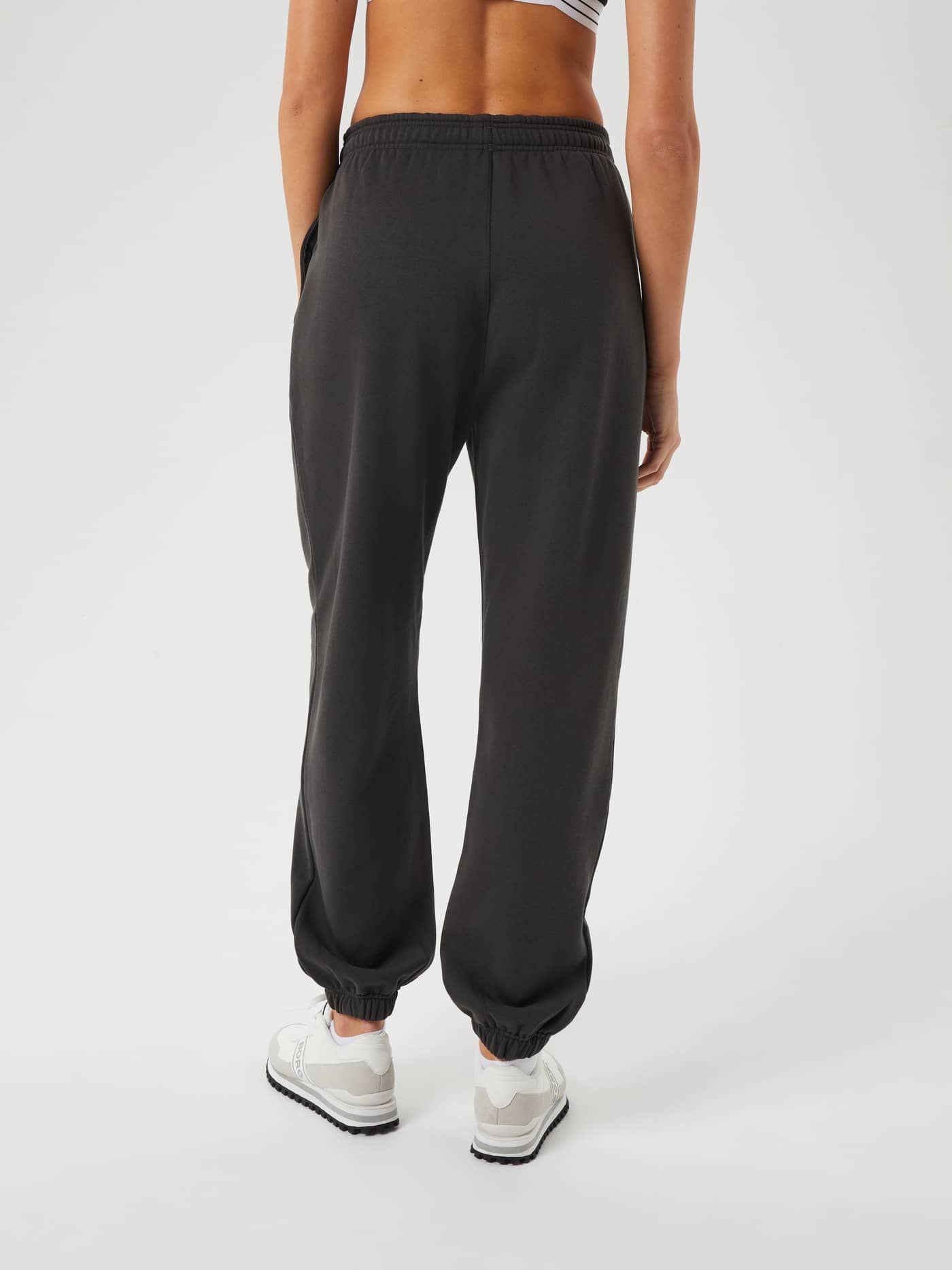 Back view of a model wearing the Studio Oversized Pants in Peat (Green), offering a stylish and relaxed fit for training. - Image 3