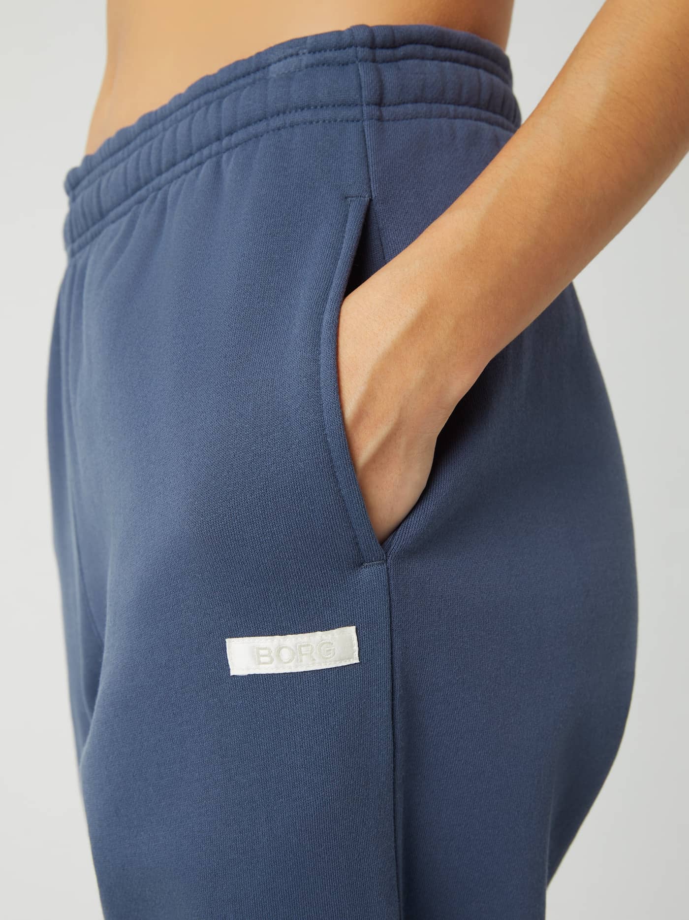 Close-up of the Studio Oversized Pants in Nightshadow Blue (Blue) featuring the side pocket and white Borg logo label. - Image 4