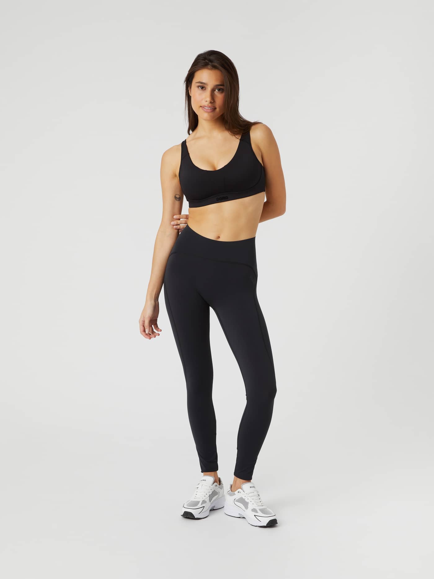 Borg Sleek Tights i Black Beauty (Svart) för dam sedda framifrån med matchande sport-bh och vita sneakers för träning. - Image 3