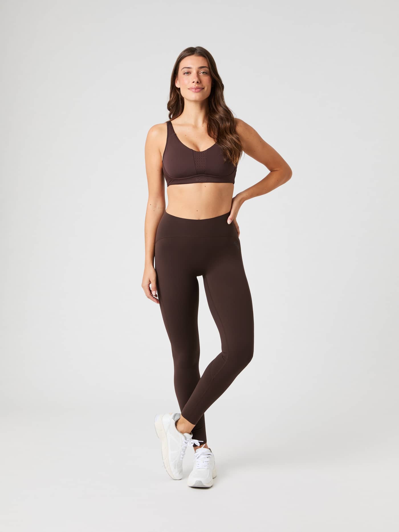 Full body front view of a woman wearing the Borg Sleek Tights in Molé brown with a matching sports bra. - Image 3
