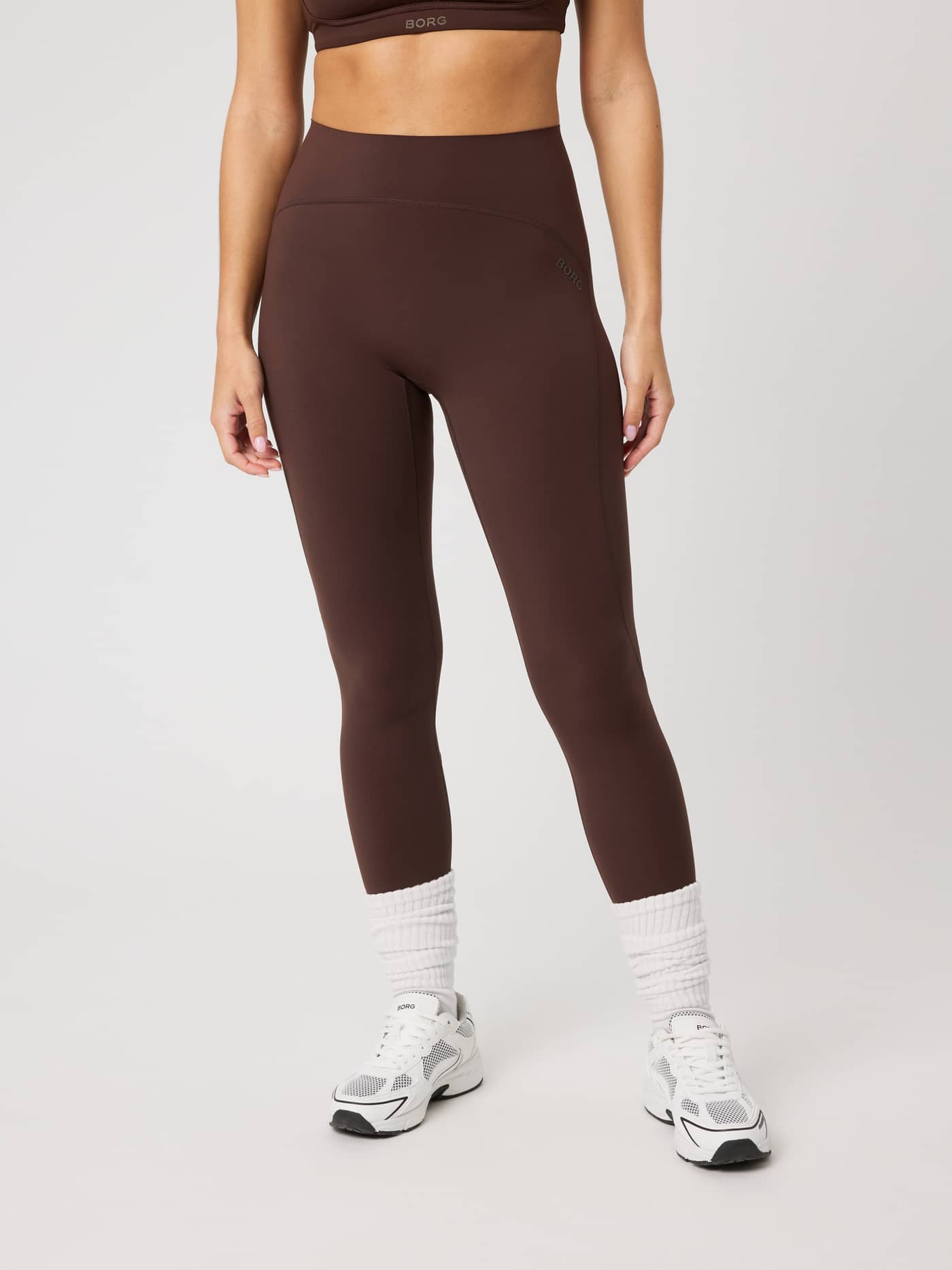 Vooraanzicht van de Borg Sleek Tights in Coffee Bean (Bruin) met een hoge taille, slim fit en bruin logo voor training. - Image 1
