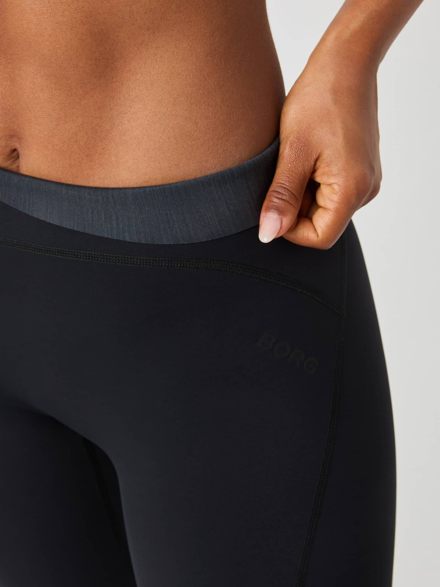 Närbild på Borg Sleek Tights i Black Beauty (Svart) med fokus på hög midja och en diskret logotyp på låret för träning. - Image 5