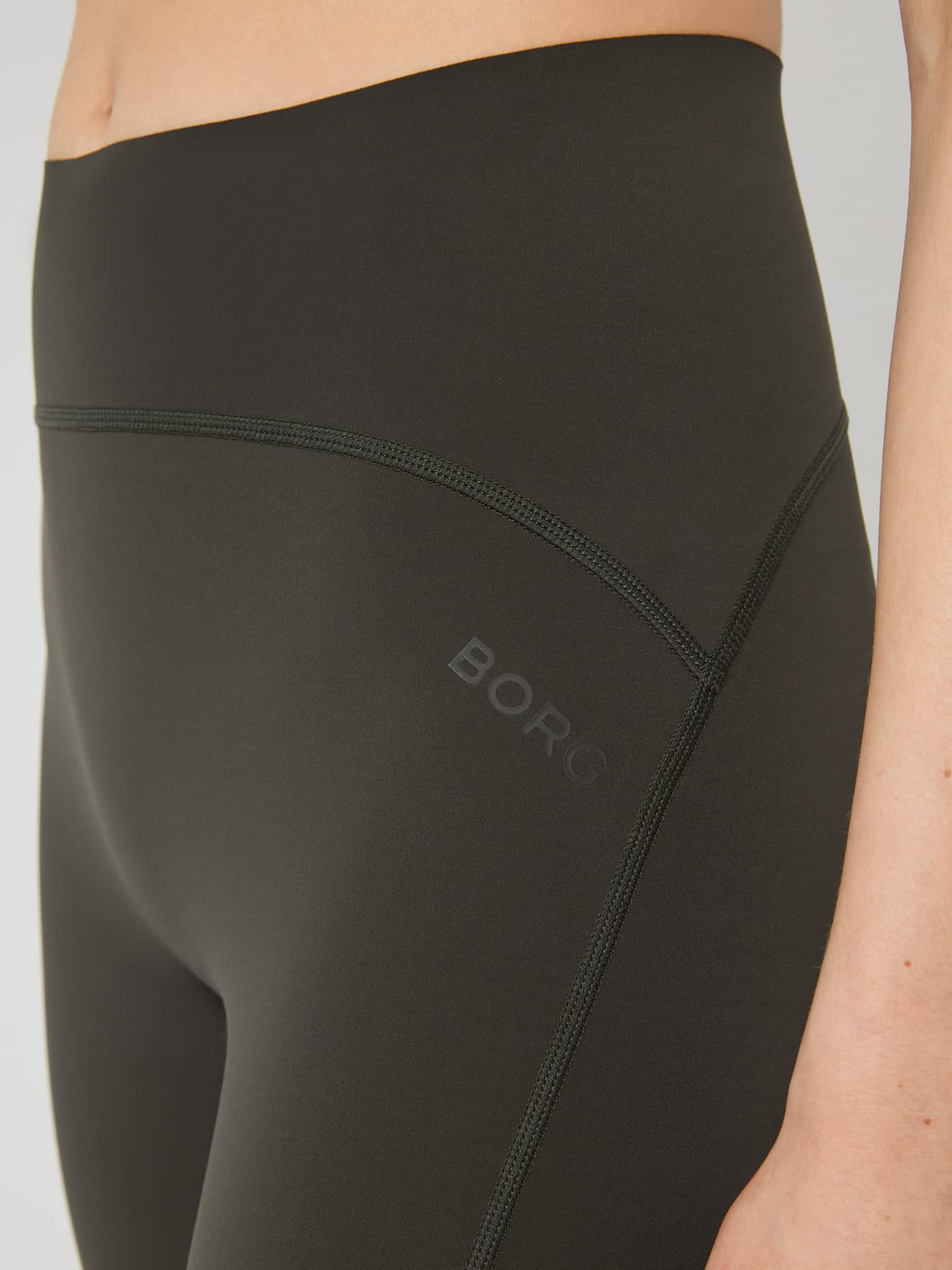 Nahaufnahme der Borg Sleek Tights in Peat (Grün) mit hohem Bund, dunklem Logo und schlanker Passform für das Training. - Image 4