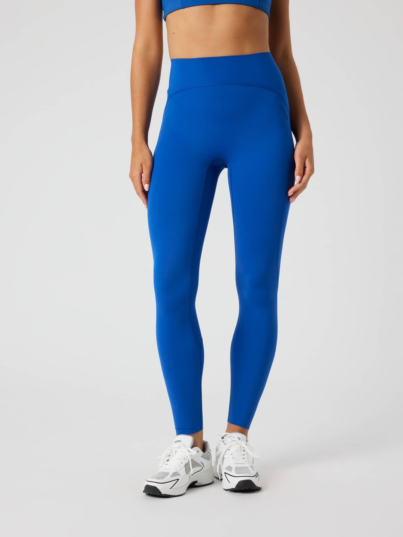 Front view of a woman wearing high-waisted Borg Sleek Tights in Monaco Blue (Blue) for a slim fit during training. - Image 1