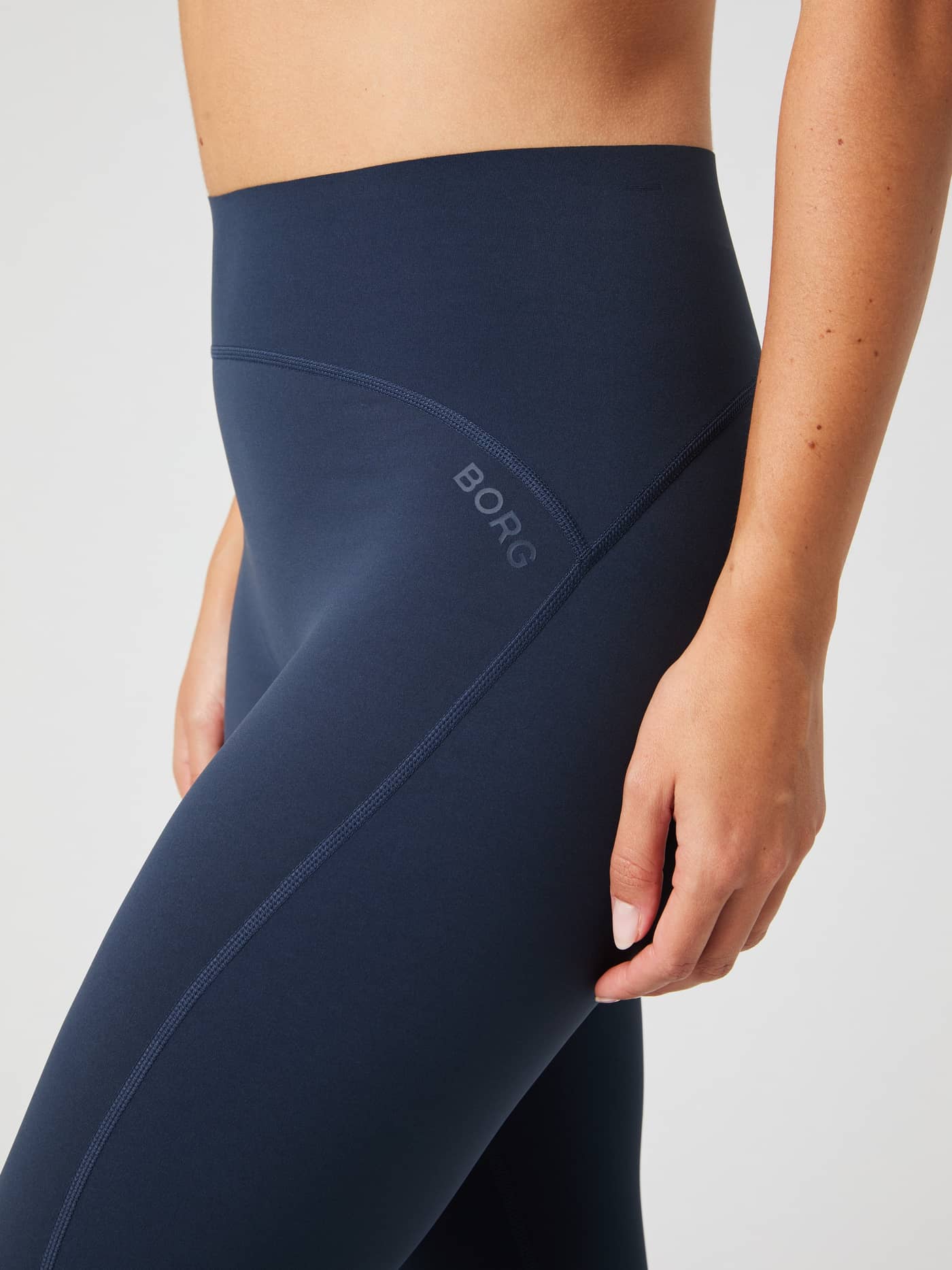 Close-up detail of the Borg Sleek Tights in navy, focusing on the high waistband and the signature BORG logo on the hip. - Image 4