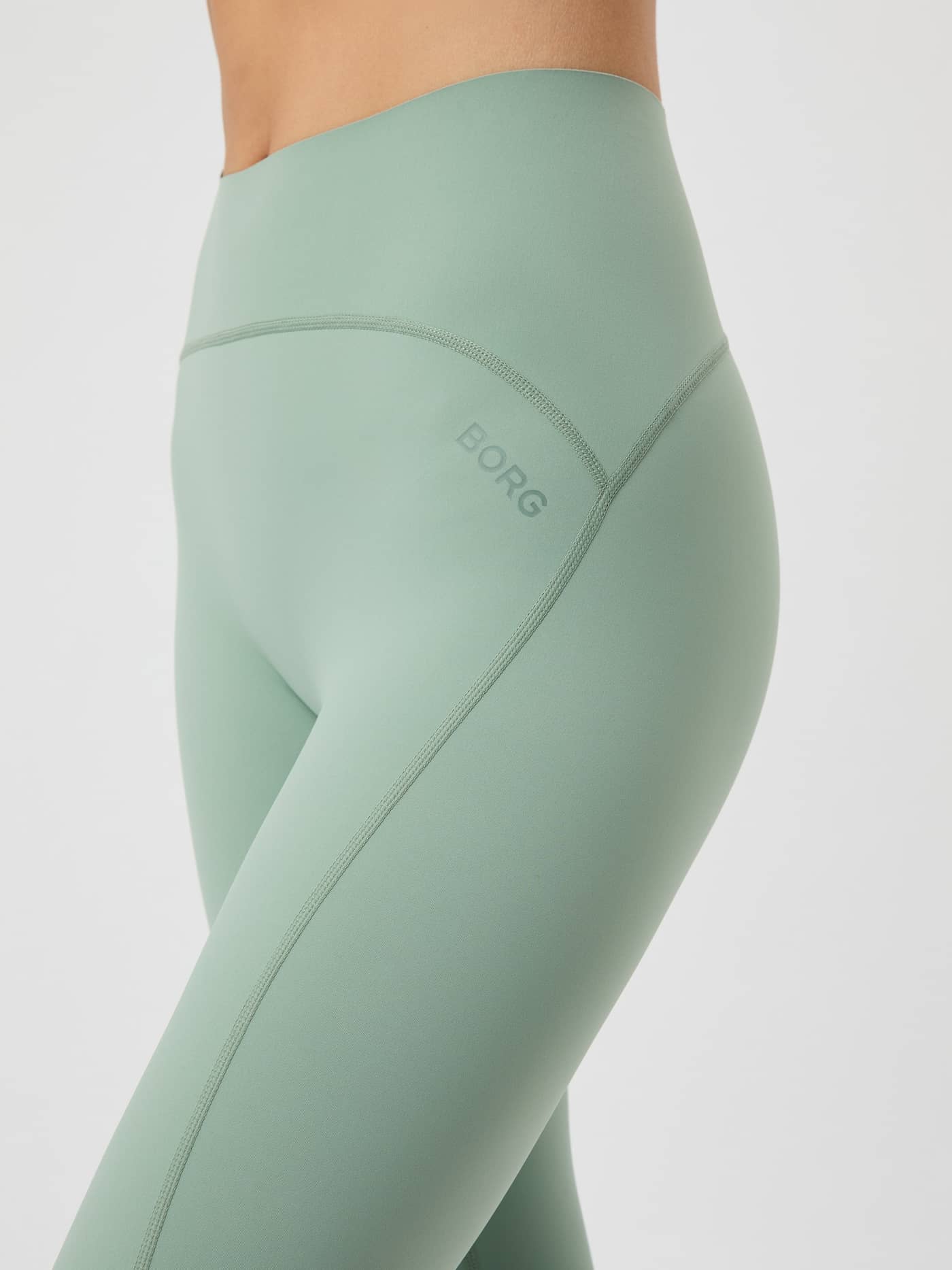Close-up side view of the Borg Sleek Tights in Lily Pad green, showing the high waist, seam detail and logo on the hip. - Image 4