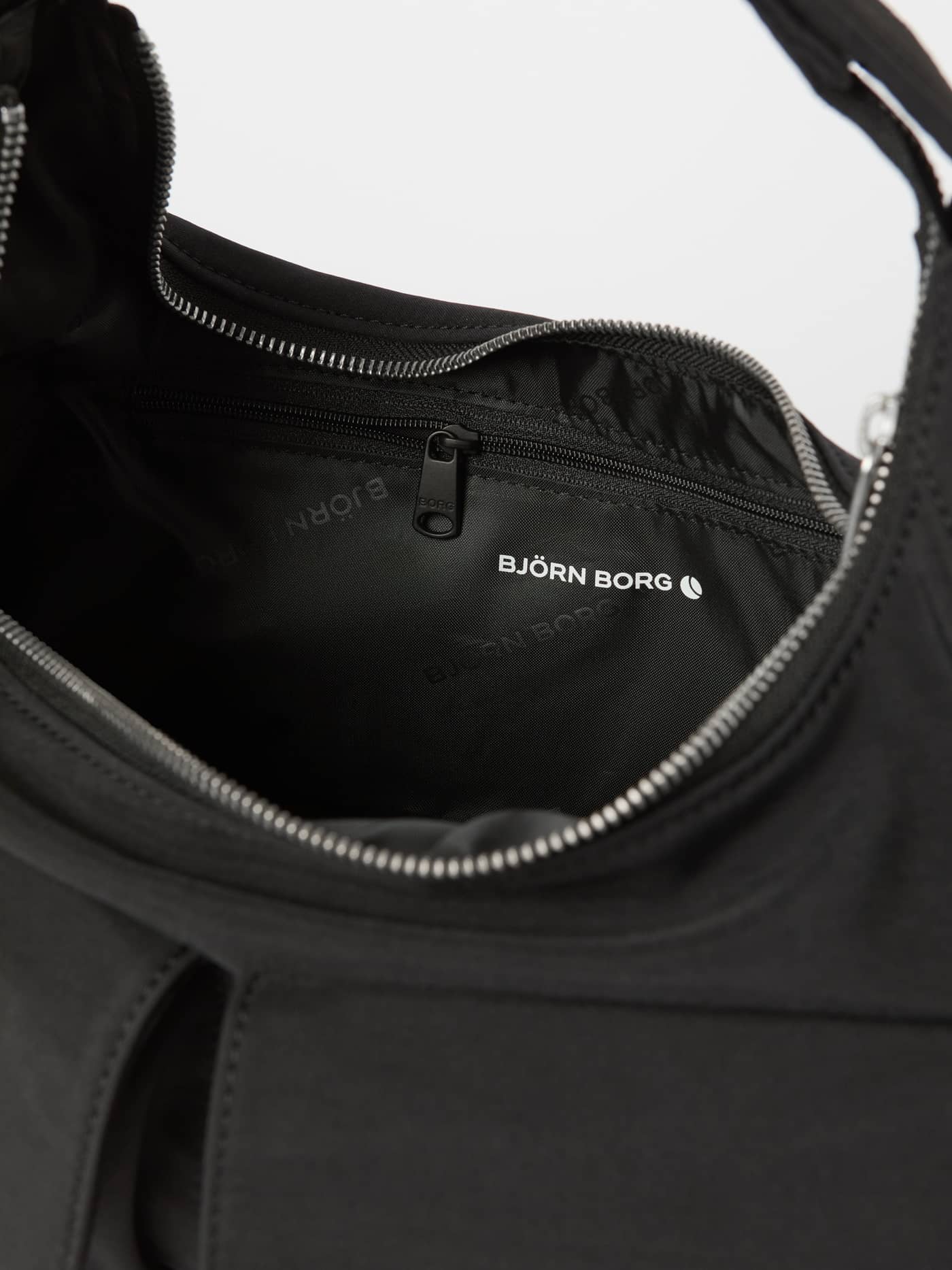 Interior detail of the Borg Cargo Shoulder Bag in Black Beauty (Black) showing the zippered pocket and white logo. - Image 3