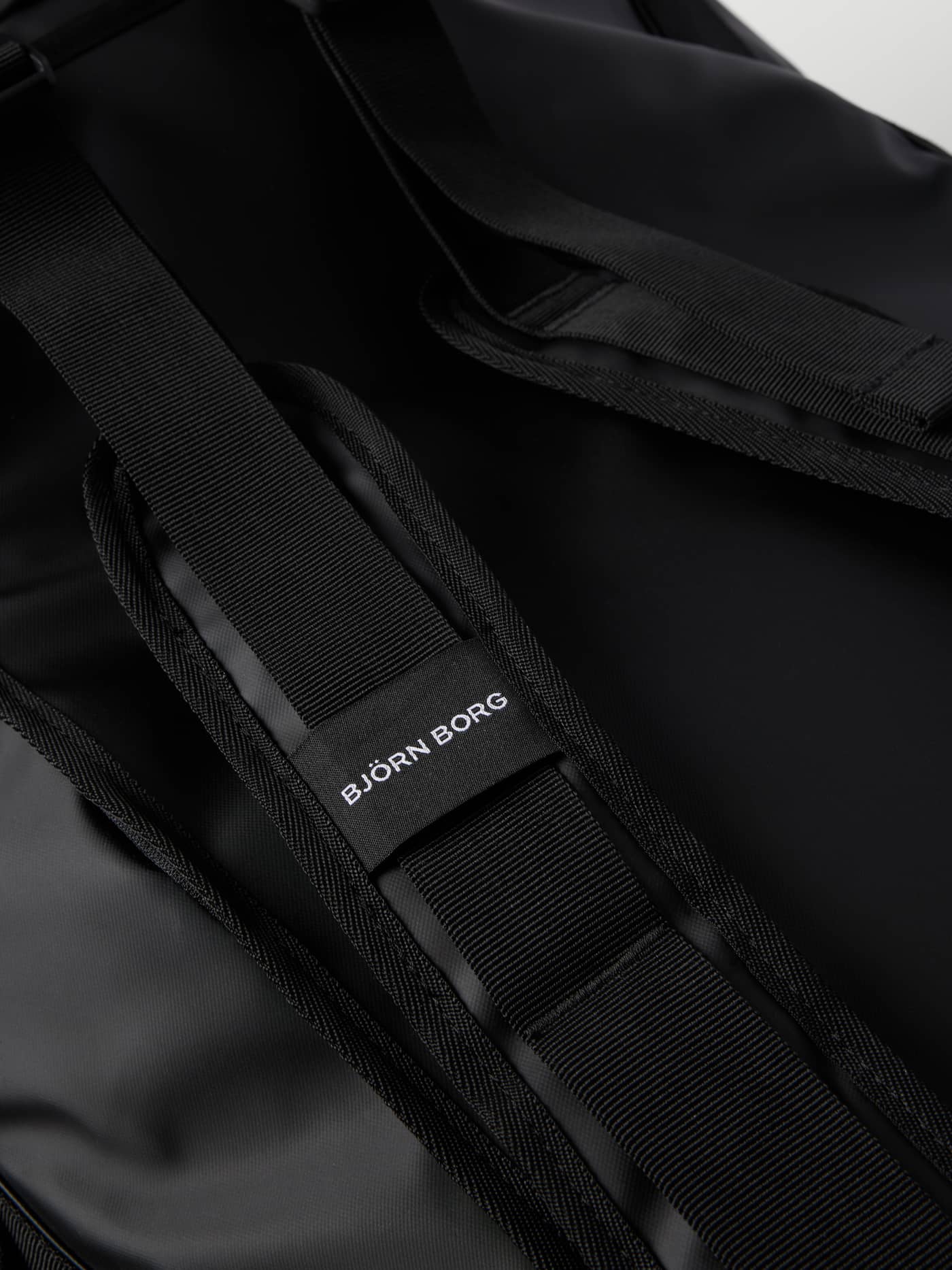 Nahaufnahme der strapazierfähigen Rucksackgurte der Borg Travel Duffle Bag 120L in Black Beauty (Schwarz) mit weißem Logo. - Image 6