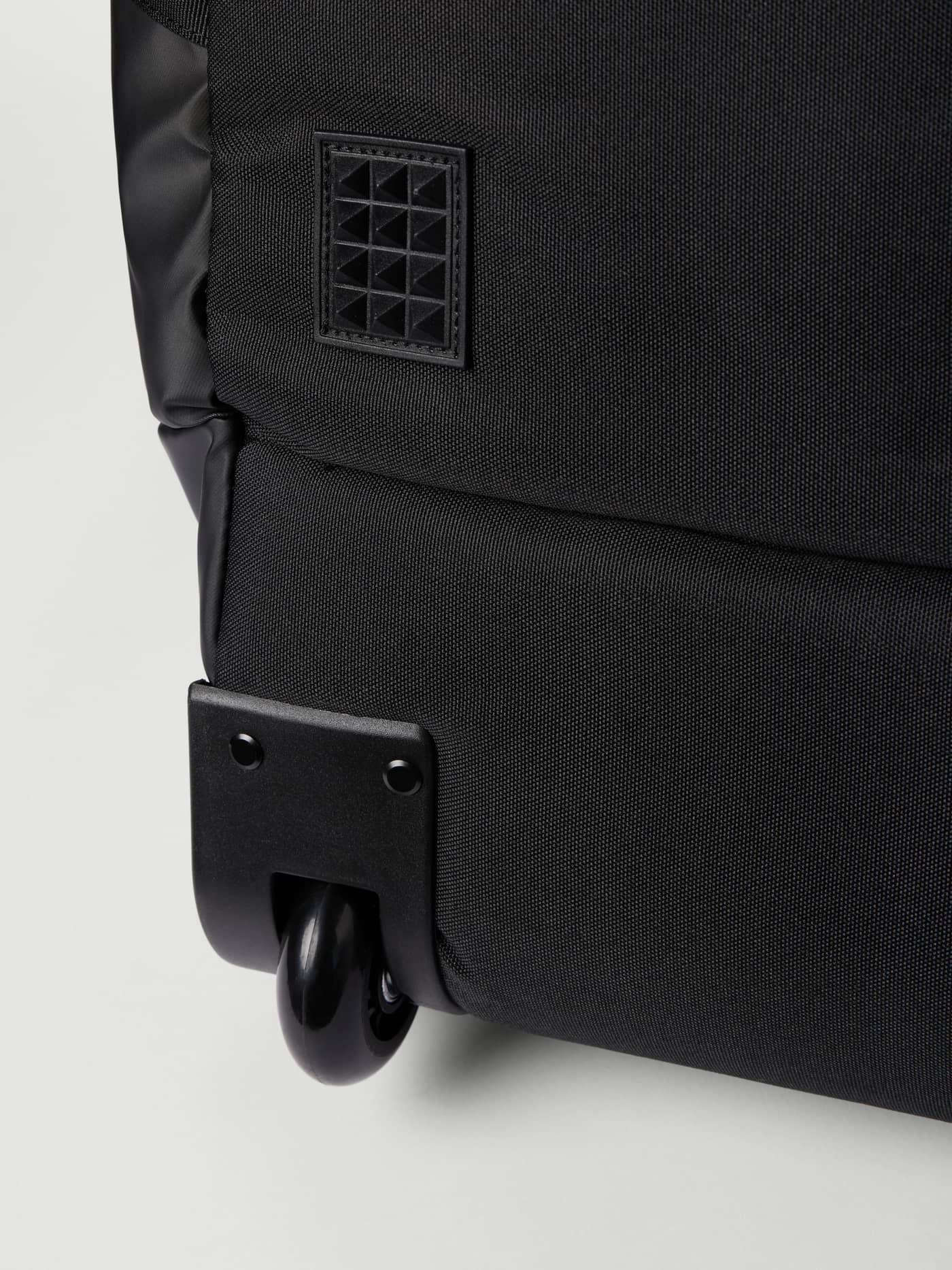 Detailansicht des Trolley-Rads und TPE-beschichteten Materials der Borg Travel Duffle Bag 120L in Black Beauty (Schwarz). - Image 7