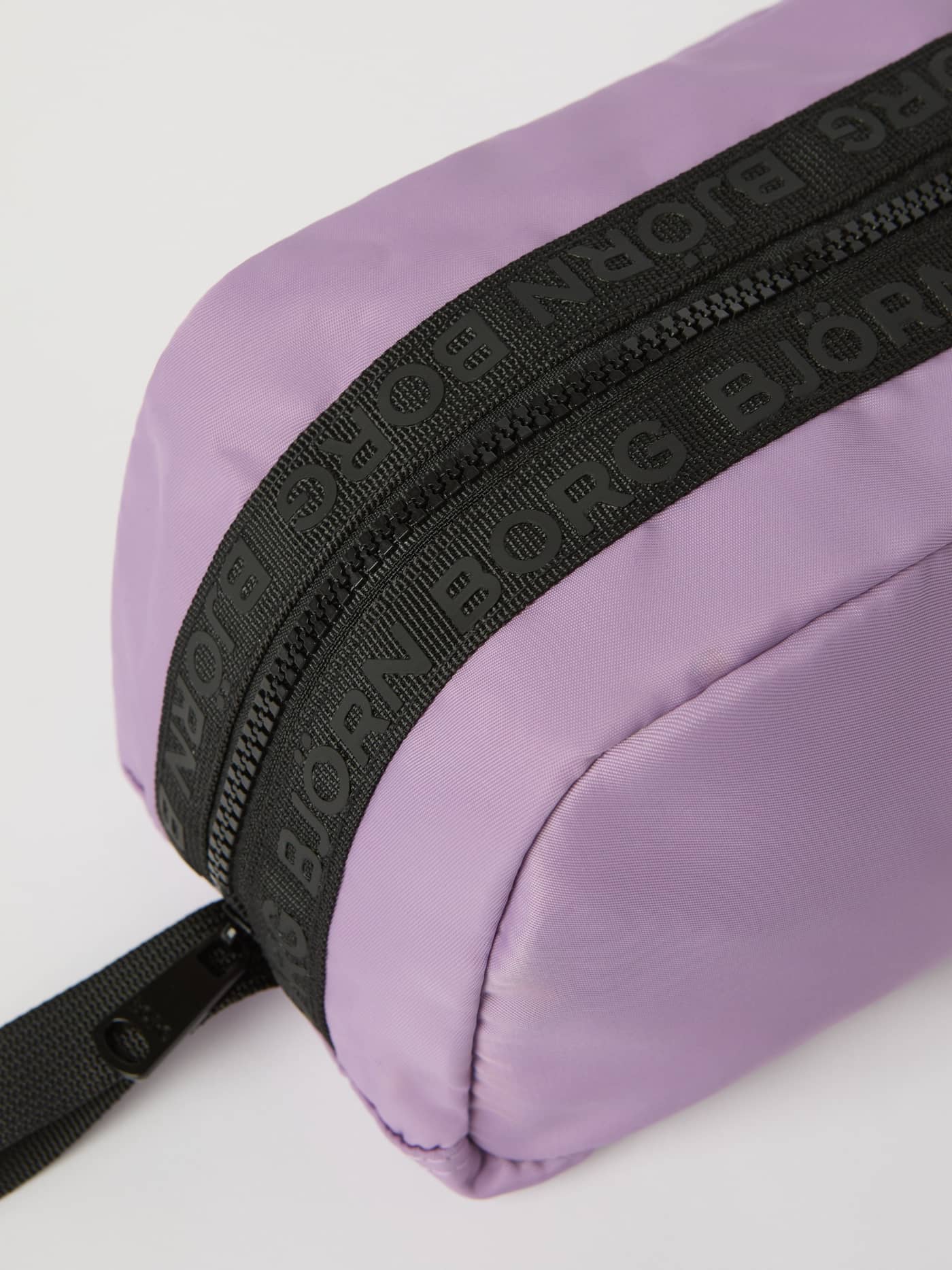 Detaljerad närbild på Borg Classic Toilet Case i Purple Sage (Lila) med svarta märkesdragkedjor på slitstarkt material. - Image 3