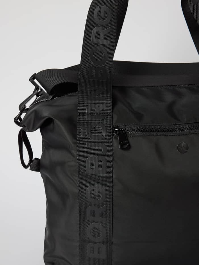 Close-up of the Borg Classic Sports Bag 28L in Black Beauty (Black), showing the black logo straps and zippered pocket. - Image 4