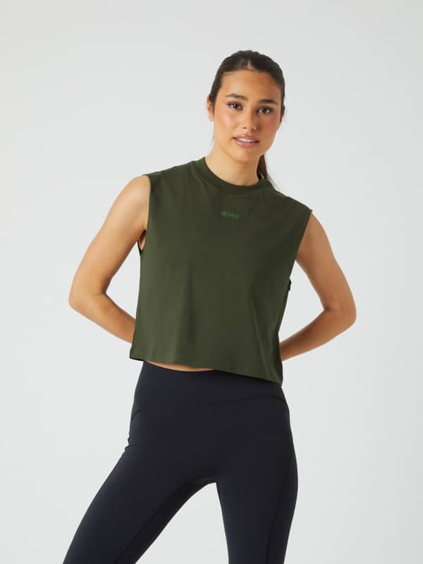 Front view of a woman wearing the loose-fitting Borg Cropped Tank in Duffel Bag (Green) for training.