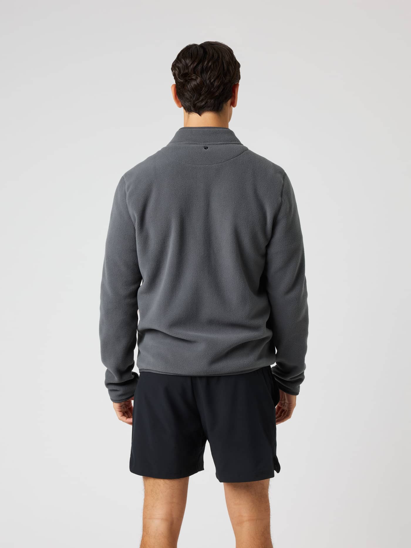 Back view of a man wearing the Borg Full Zip Fleece in Asphalt (Black), a training midlayer with a tennis ball detail. - Image 2