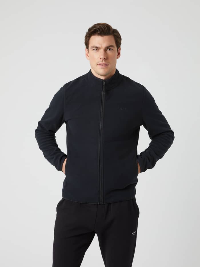 Front view of a man wearing the black Borg Full Zip Fleece with his hands in the pockets.