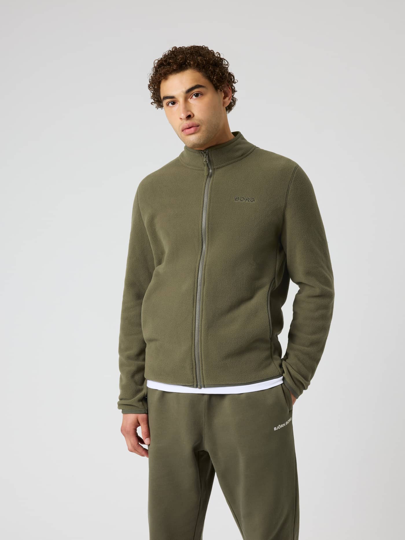 Front view of a man in the Borg Full Zip Fleece in Kalamata (Green), a soft training jacket with a full-length front zipper. - Image 2