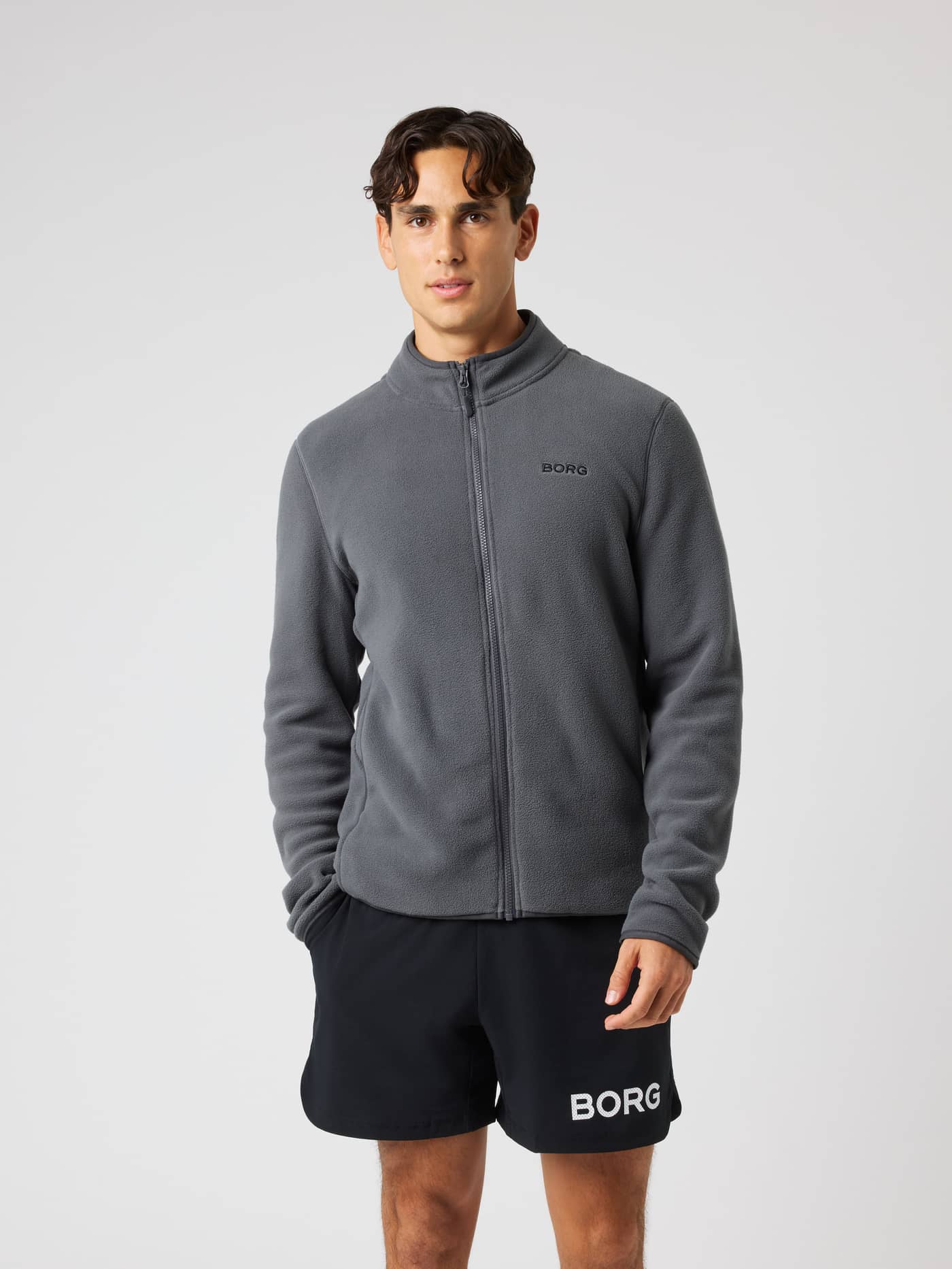 Vooraanzicht van een model in de Borg Full Zip Fleece in Asphalt (Zwart) voor training met een zwart borstlogo. - Image 1