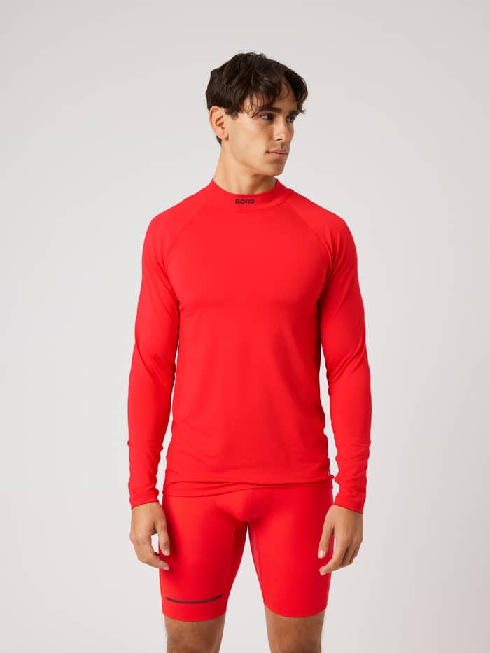 Front view of a model in the Borg Mock Neck Ls T-Shirt in Flame Scarlet (Red), a long-sleeve training top with black logo.
