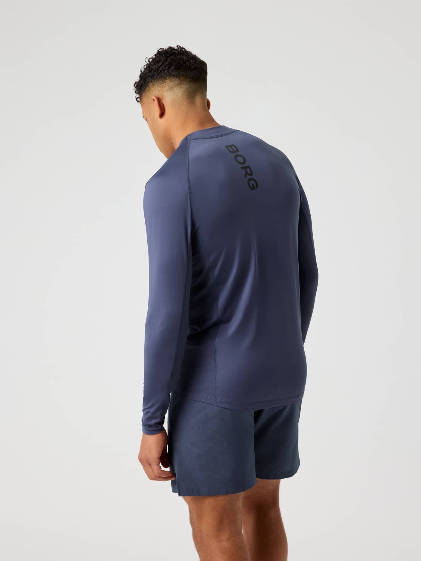 Rückansicht eines Mannes im Borg Mock Neck Ls T-Shirt in Odyssey Gray (Blau) mit schwarzem Logo für das Training. - Image 2