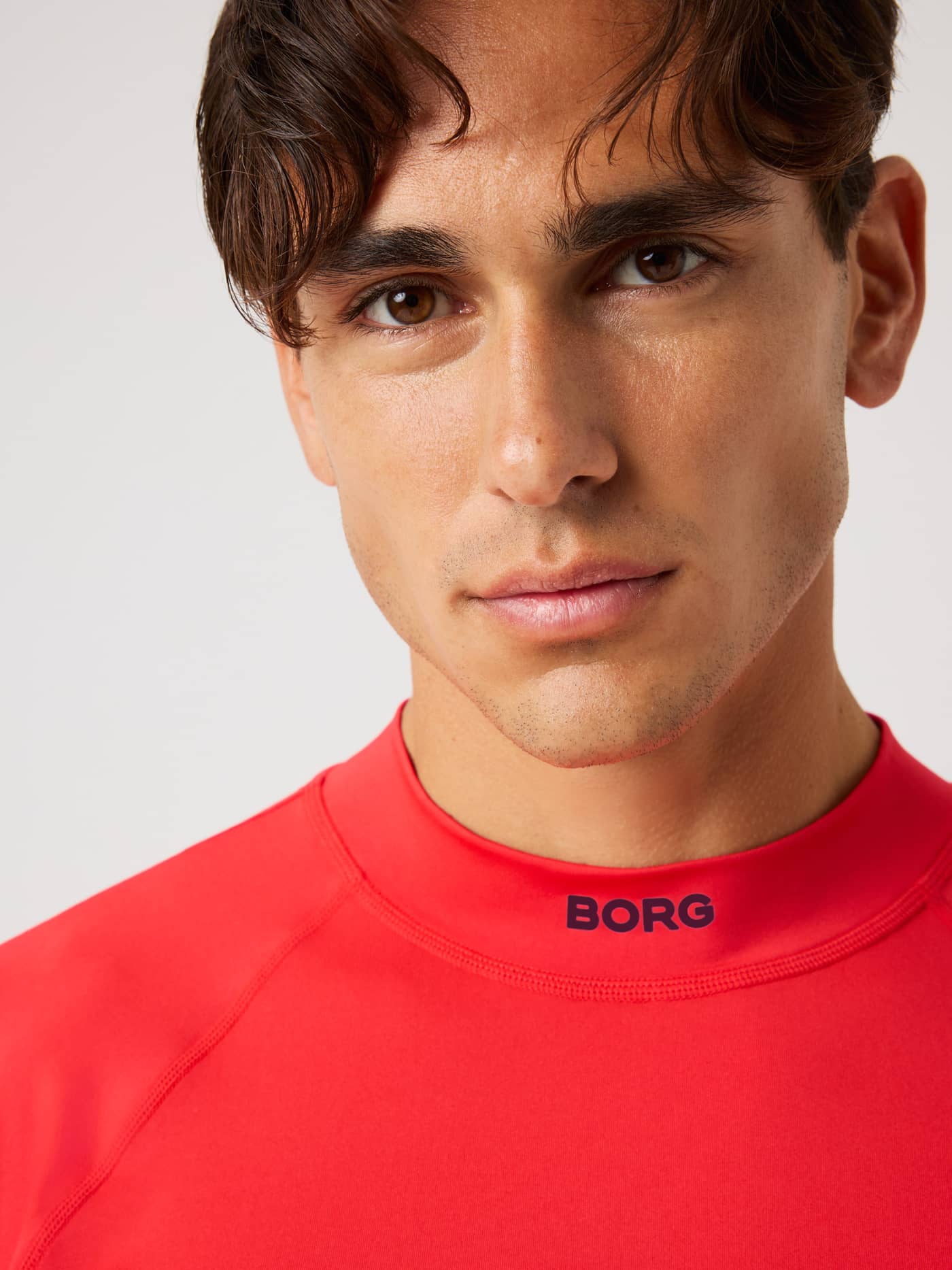 Close-up of the Borg Mock Neck Ls T-Shirt in Flame Scarlet (Red) showing the technical mock neck and logo for training. - Image 5