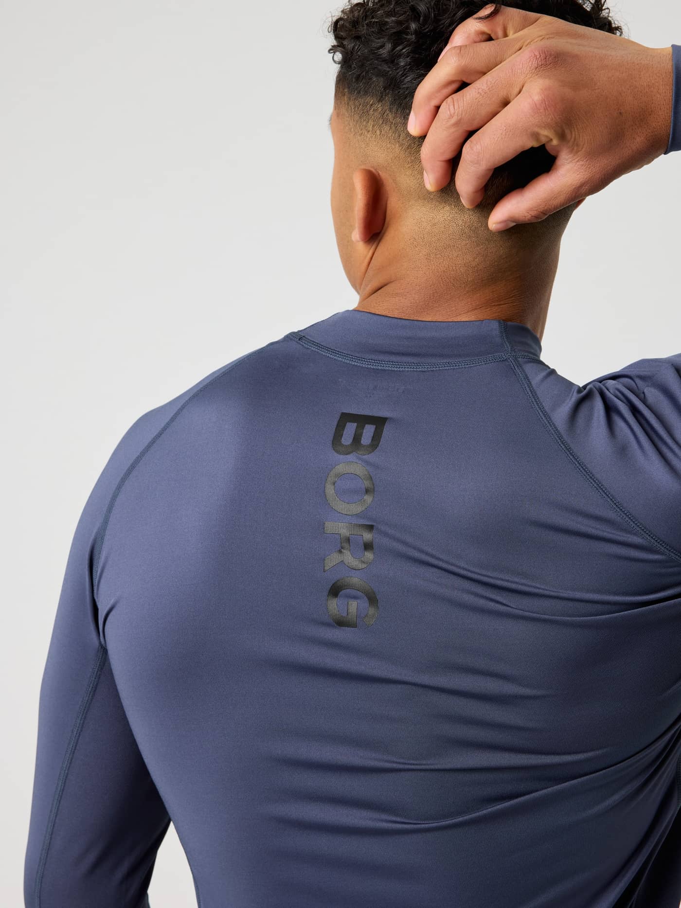 Nahaufnahme der Rückansicht des Borg Mock Neck Ls T-Shirt in Odyssey Gray (Blau) für das Herren-Training mit schwarzem Logo. - Image 4