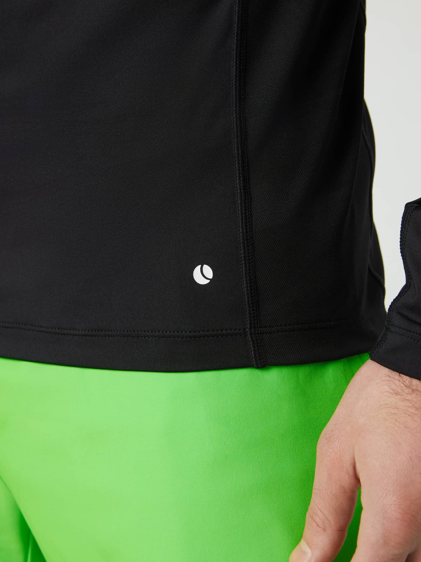 Close-up of the tennis ball logo on the hem of the black Borg Mock Neck Long Sleeve T-shirt. - Image 5