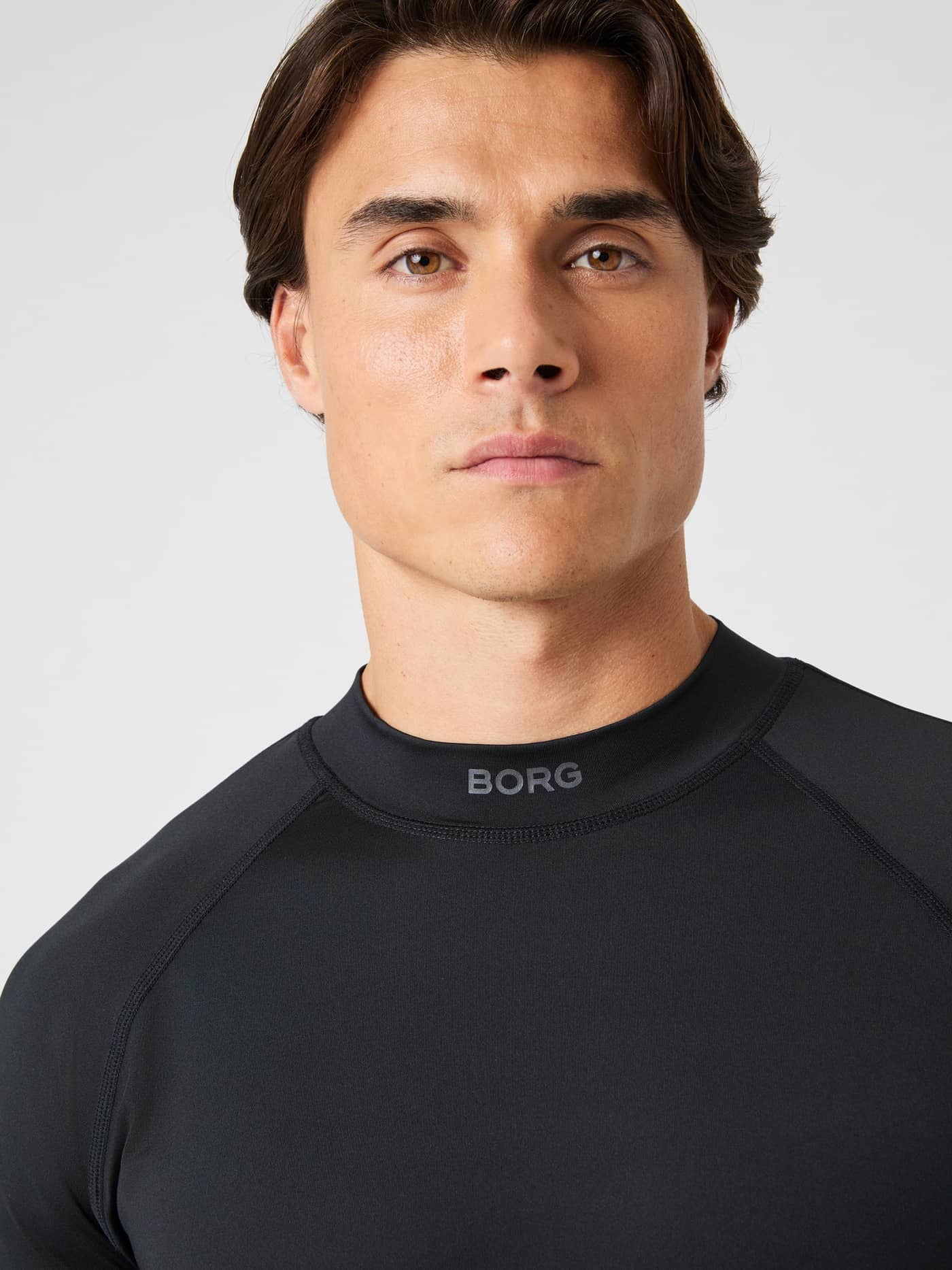 Primer plano del logo gris en la Borg Mock Neck Ls T-Shirt en Black Beauty (Negro) para entrenamiento. - Image 4