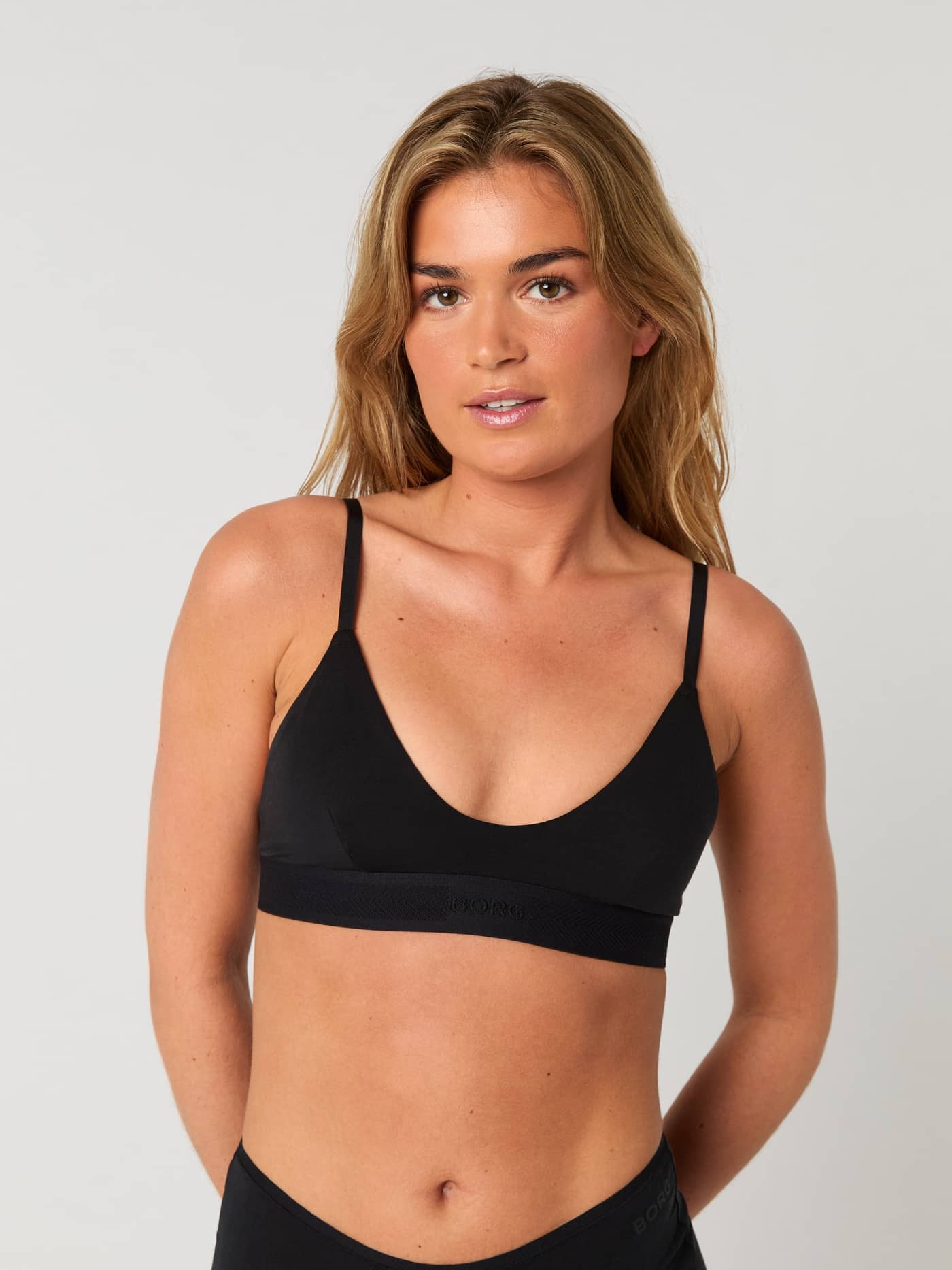 Front view of a woman wearing the black Core Lyocell Bra, featuring a soft, comfortable fit and logo elastic band. - Image 2