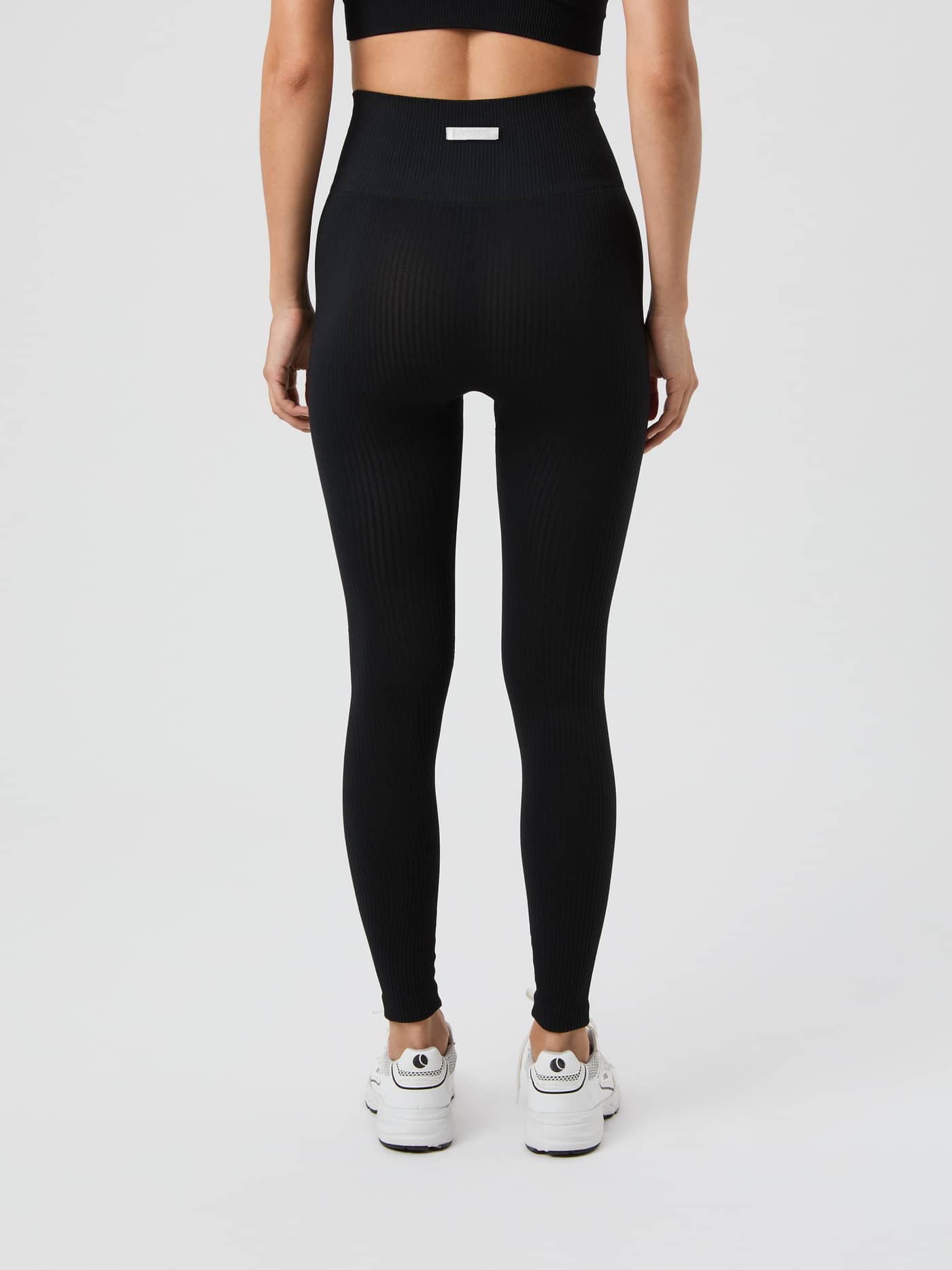 Back view of a model wearing the black Studio Seamless Ribbed Tights. - Image 3