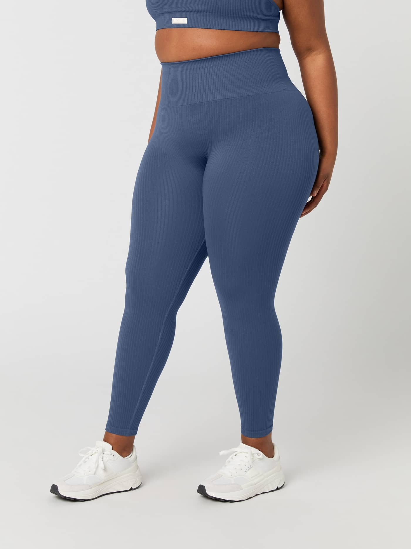 Side view of a model wearing the Björn Borg Studio Seamless Ribbed Tights in Nightshadow Blue. - Image 4