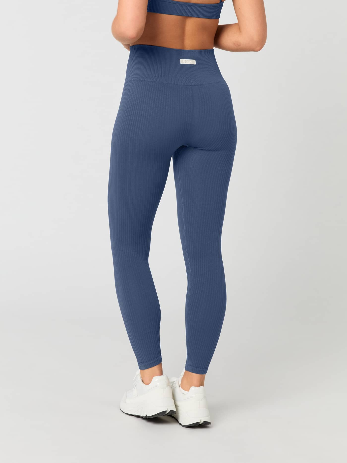 Back view of a woman wearing Björn Borg Studio Seamless Ribbed Tights in Nightshadow Blue. - Image 3