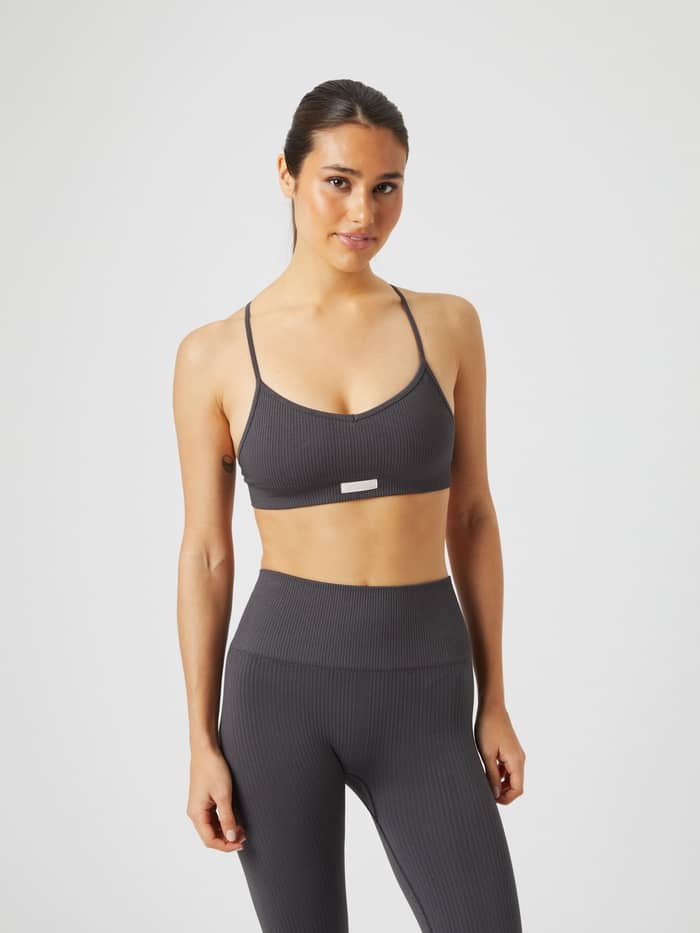 Studio Seamless Ribbed Strap Bra in Asphalt (Grau) an einem Model mit gerippter Textur und hellem Logo für Training. - Image 1