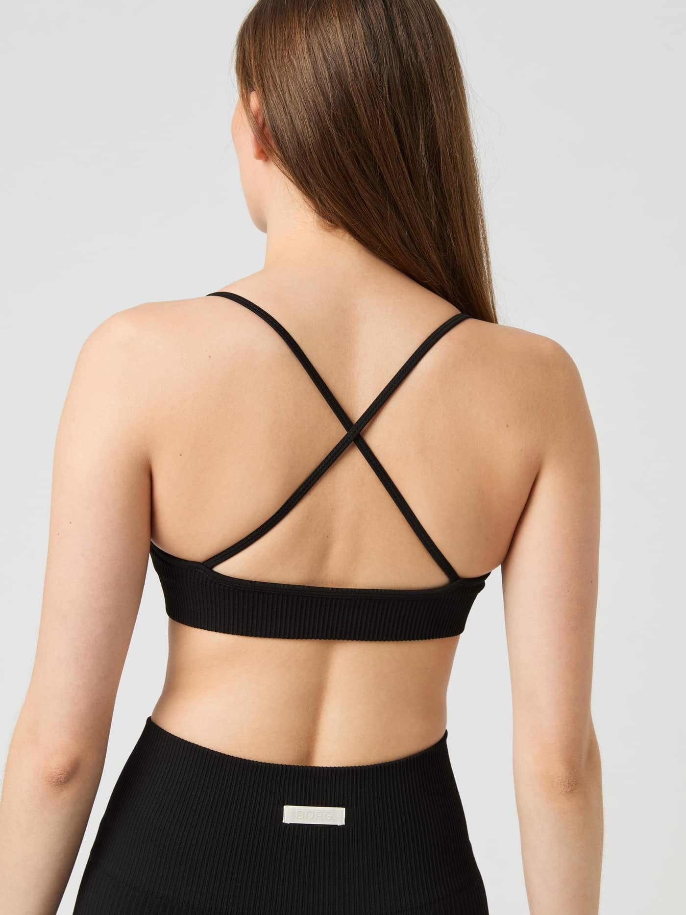 Vue de dos du Studio Seamless Ribbed Strap Bra en Black Beauty (Noir) avec fines bretelles croisées et maille côtelée. - Image 2