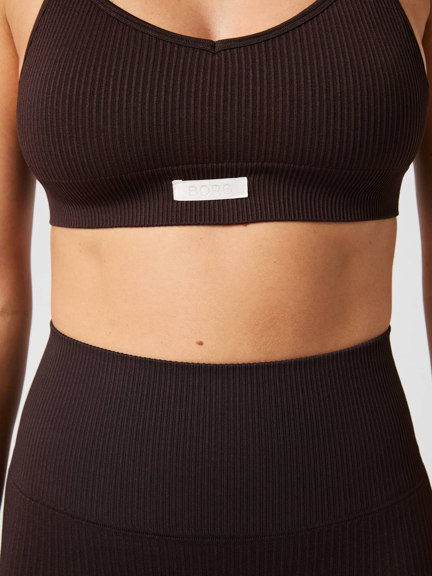 Close-up van de Studio Seamless Ribbed Strap Bra in Molé (Bruin) met geribbelde textuur en wit BORG-logolabel. - Image 4