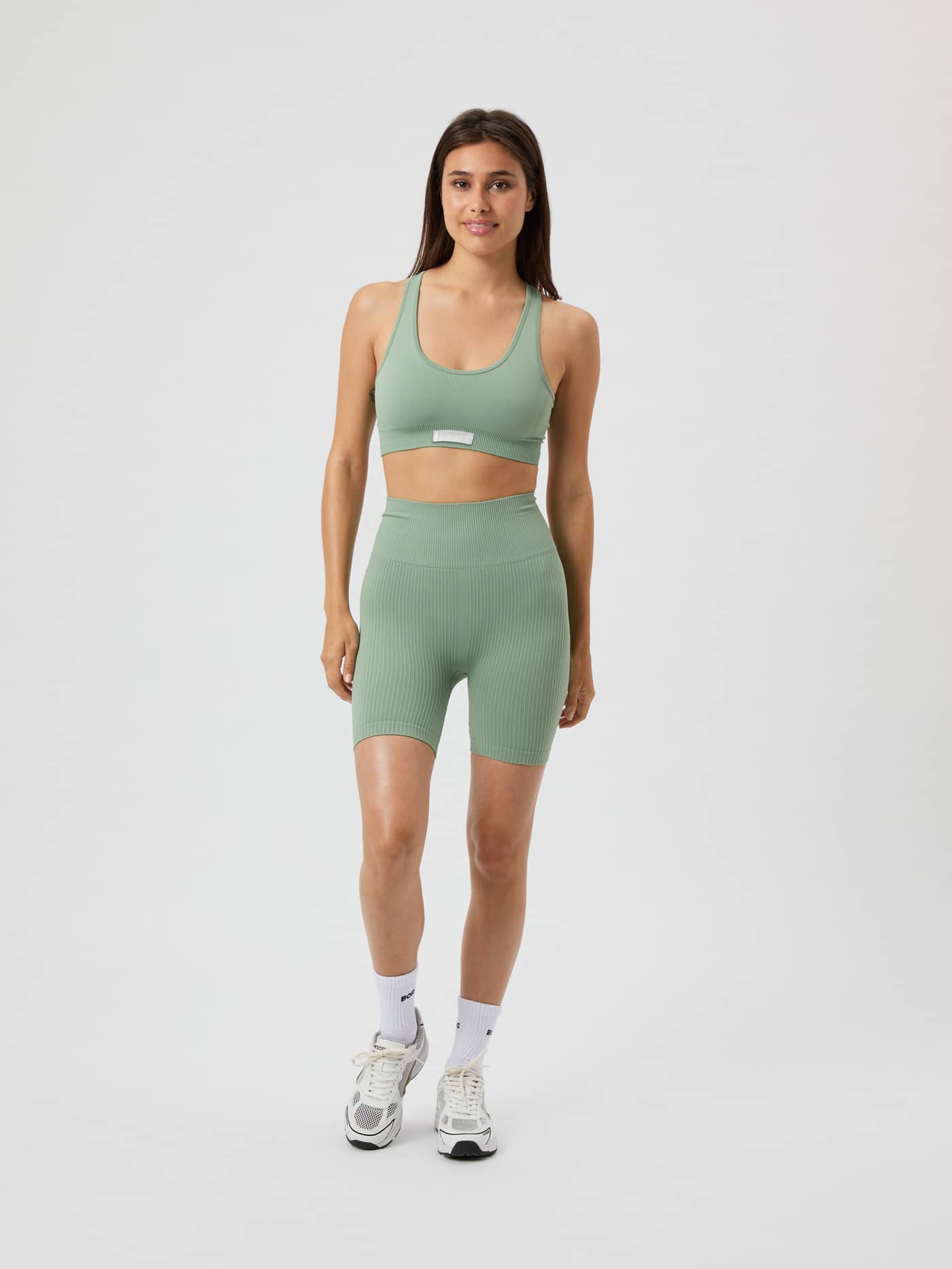 Vue de face d'un mannequin en Studio Seamless Low Sports Bra Lily Pad (Vert) sans coutures avec short assorti. - Image 3