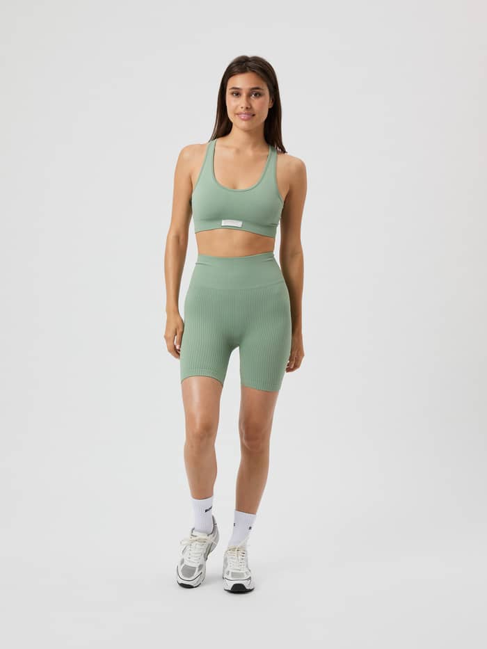 Vorderansicht eines Models im Studio Seamless Low Sports Bra in Lily Pad (Grün) und passenden Shorts für das Training. - Image 3
