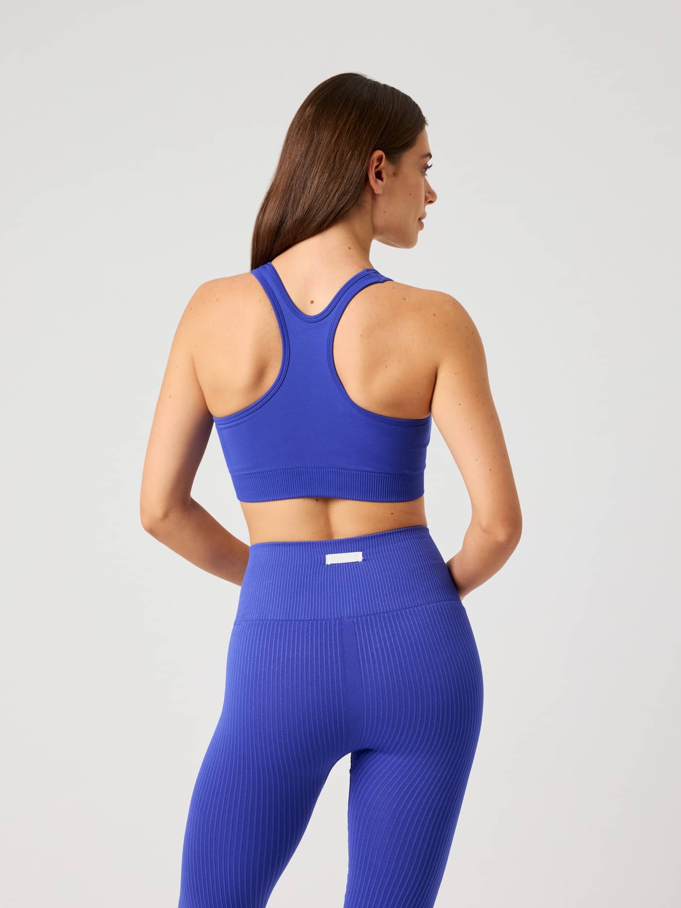 Back view of a woman wearing the seamless Studio Seamless Low Sports Bra in Clematis Blue (Blue) for training. - Image 3