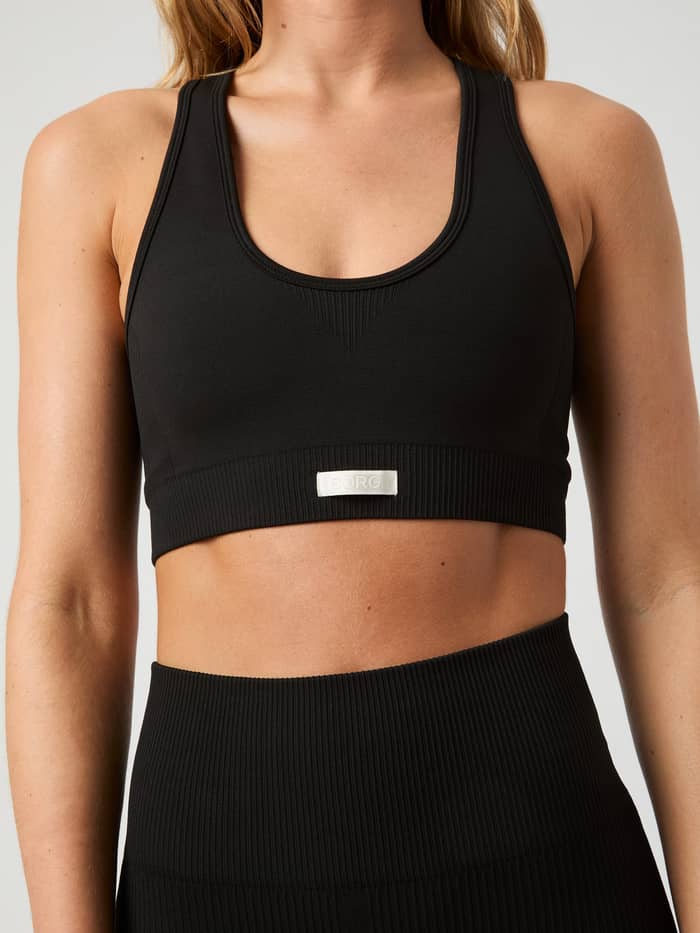 Nahaufnahme der Vorderansicht eines Models im Studio Low Seamless Sports Bra in Schwarz mit Rippstruktur für das Training. - Image 2