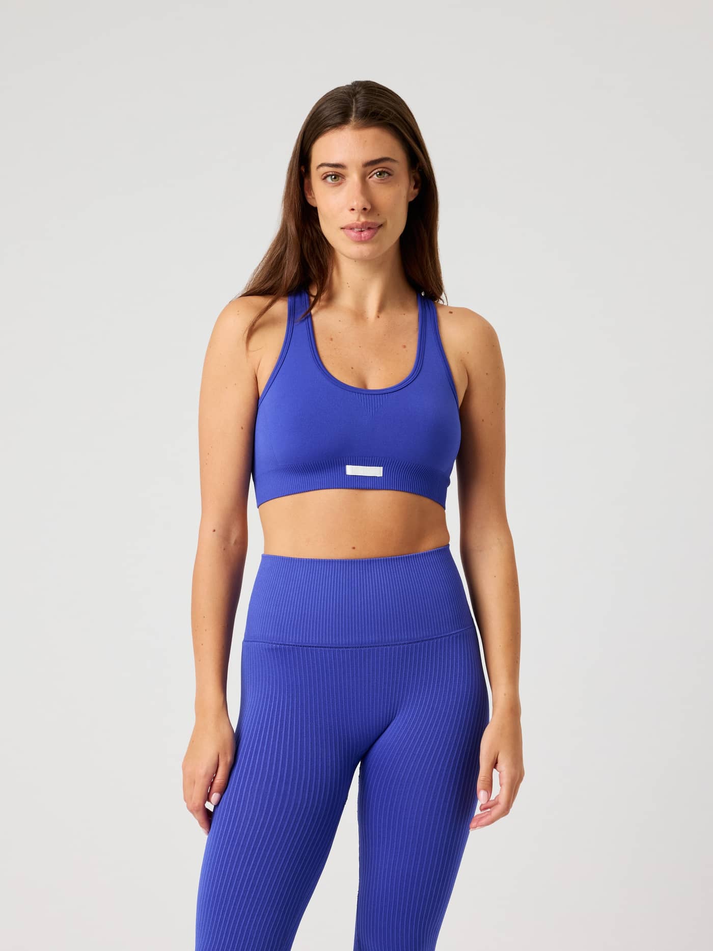 Front view of a woman in the training Studio Seamless Low Sports Bra in Clematis Blue (Blue) with a white logo and great fit. - Image 2
