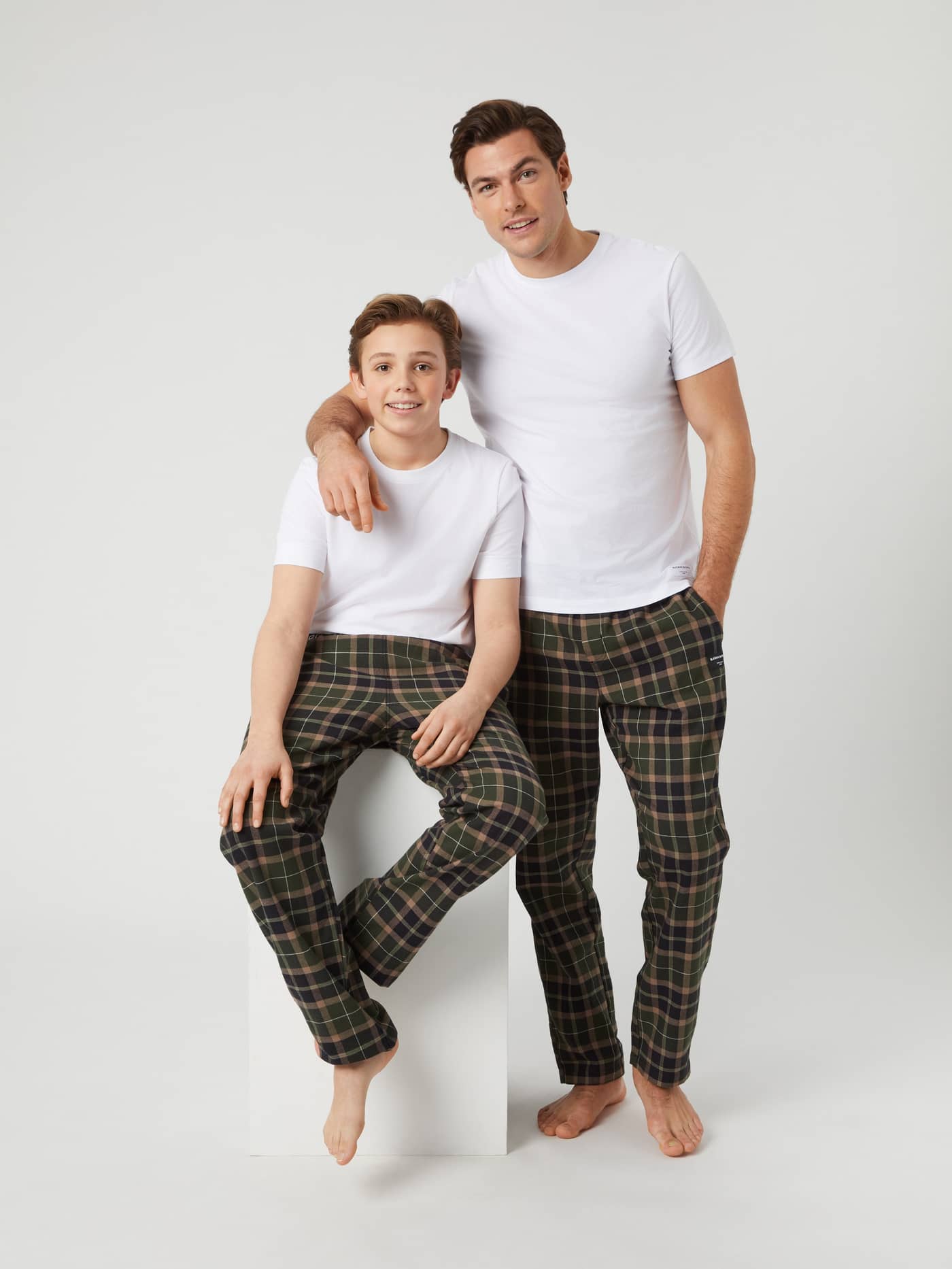 Man and kid in matching Björn Borg Core Flannel Set 2-pack in Multi (Multi) with white tees and checkered flannel pants. - Image 1