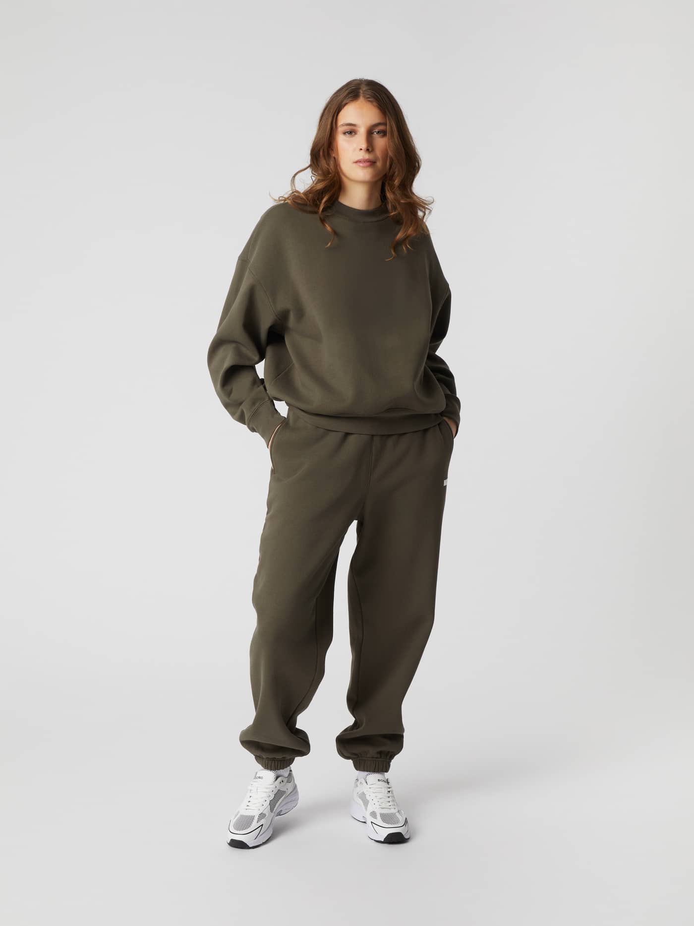 Full-body front view of a woman wearing the Björn Borg Studio Oversized Crew in Tarmac (Brown) with matching joggers. - Image 2