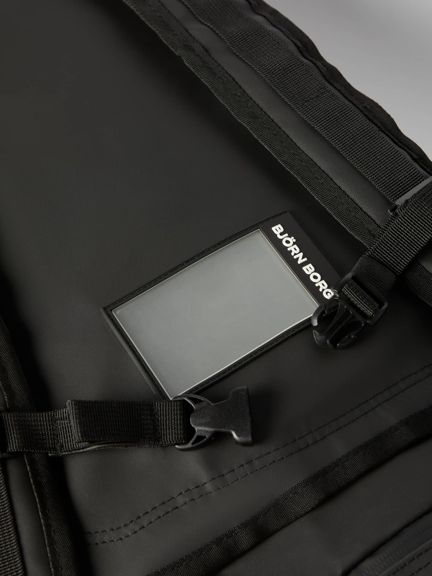 Detailed close-up of the address tag and buckle on the Borg Duffle Bag 75L in Black Beauty (Black). - Image 7